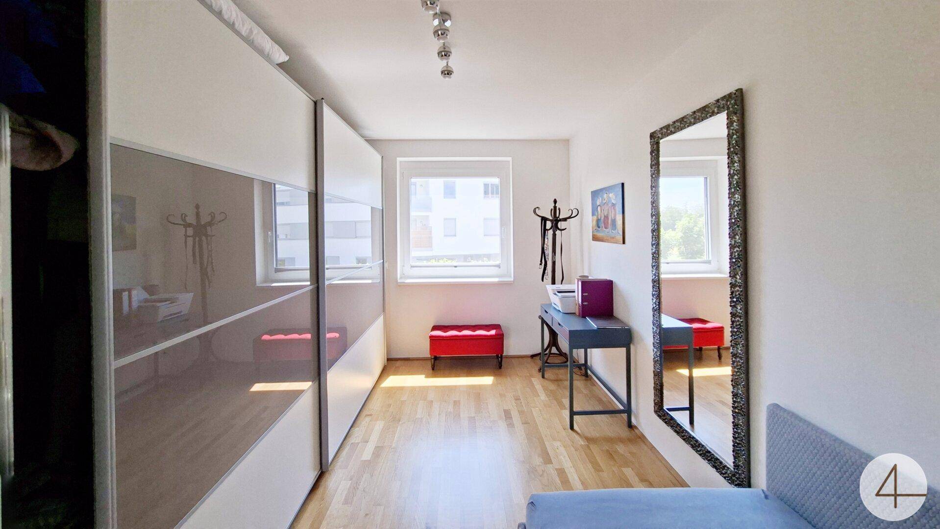 Zimmer mit Schiebetürenschrank, Schlafsofa und Fenster mit Blick nach draußen.