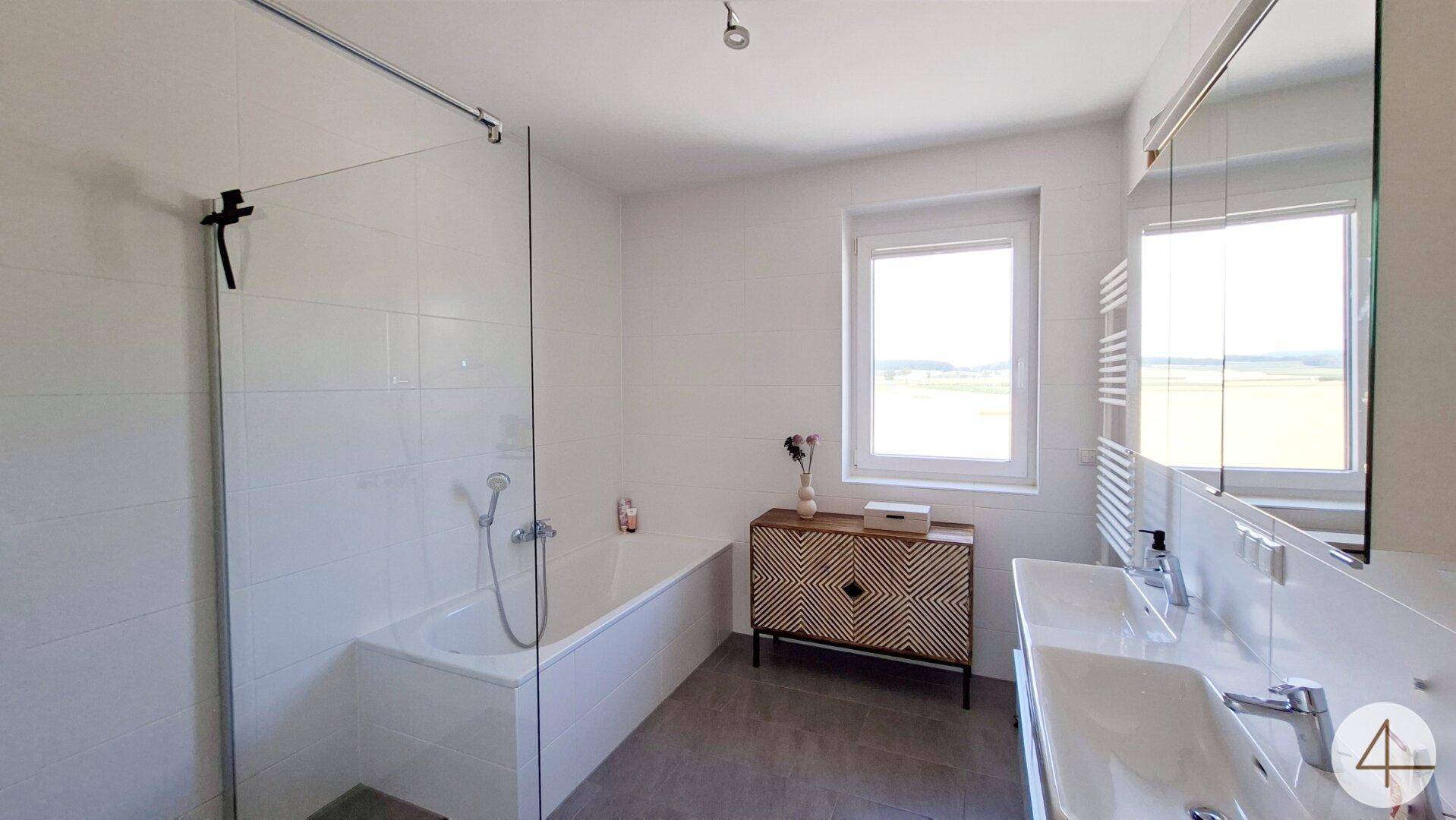Modernes Badezimmer mit Badewanne, Dusche und Doppelwaschbecken.