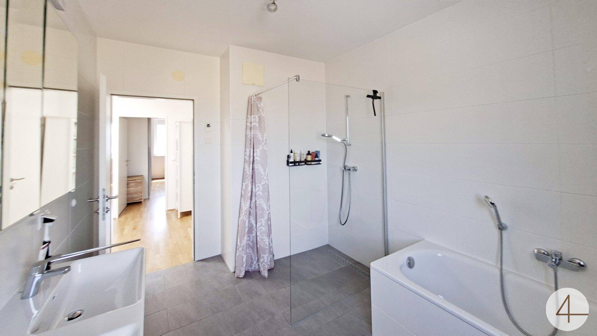 Helles Badezimmer mit Dusche, Badewanne und Doppelwaschbecken.