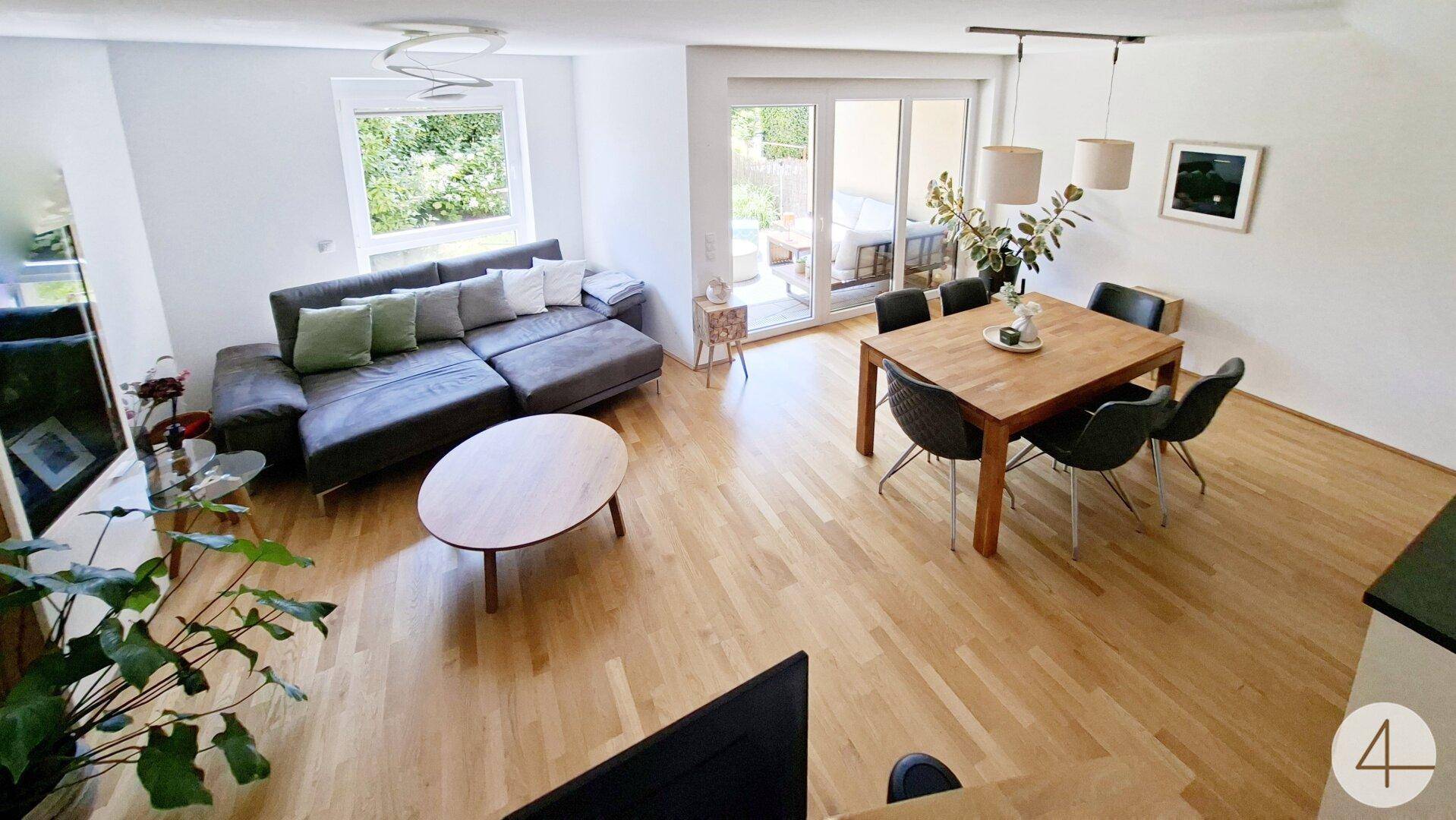 Geräumiger Wohn-Essbereich mit Holzboden, bequemer Couch und Esstisch.