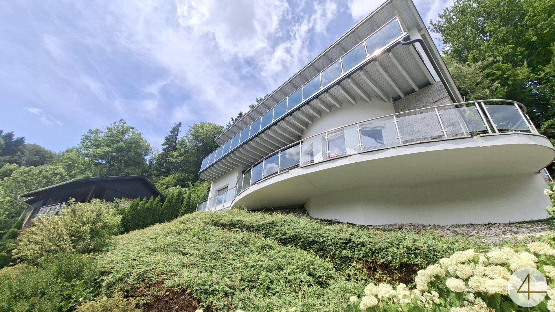 Architektonisch ansprechendes Gebäude mit geschwungenen Balkonen und viel Grün in der Umgebung.