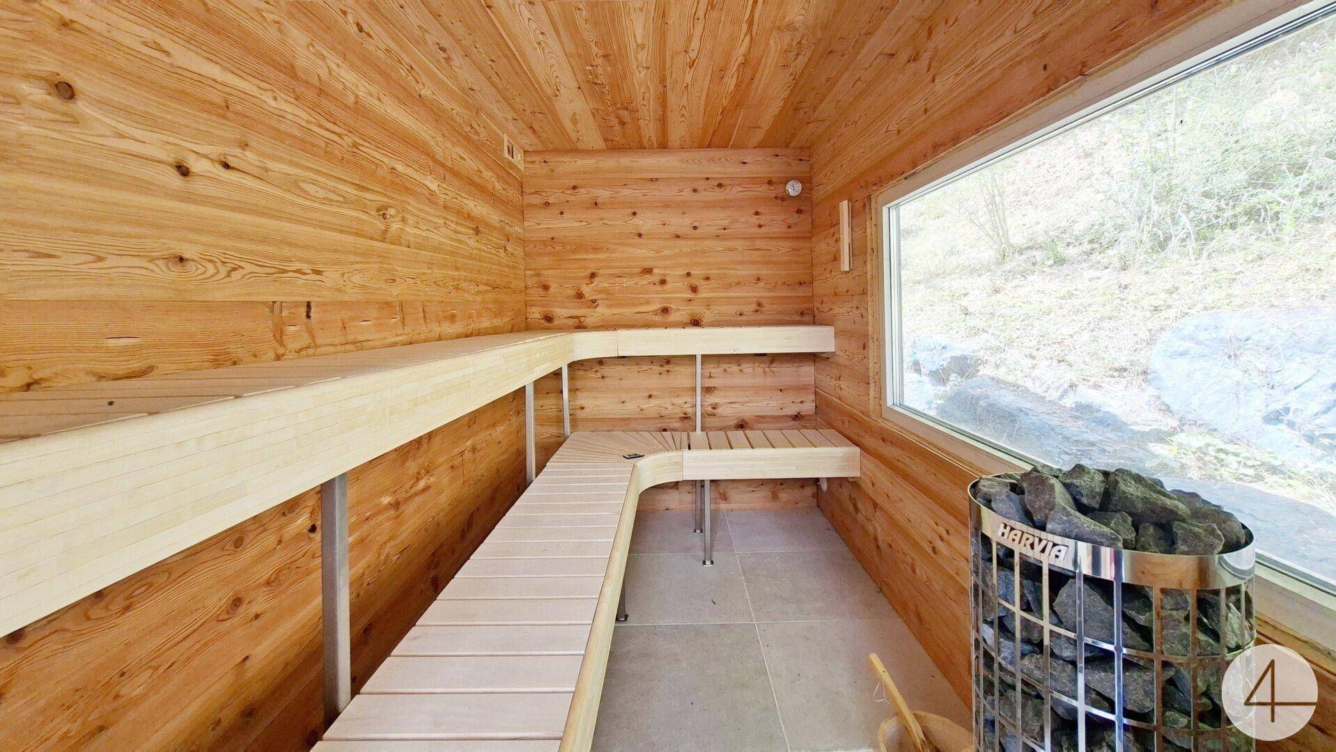 Holzverkleidete Sauna mit Sitzbänken und großem Fenster für natürlichen Lichteinfall.