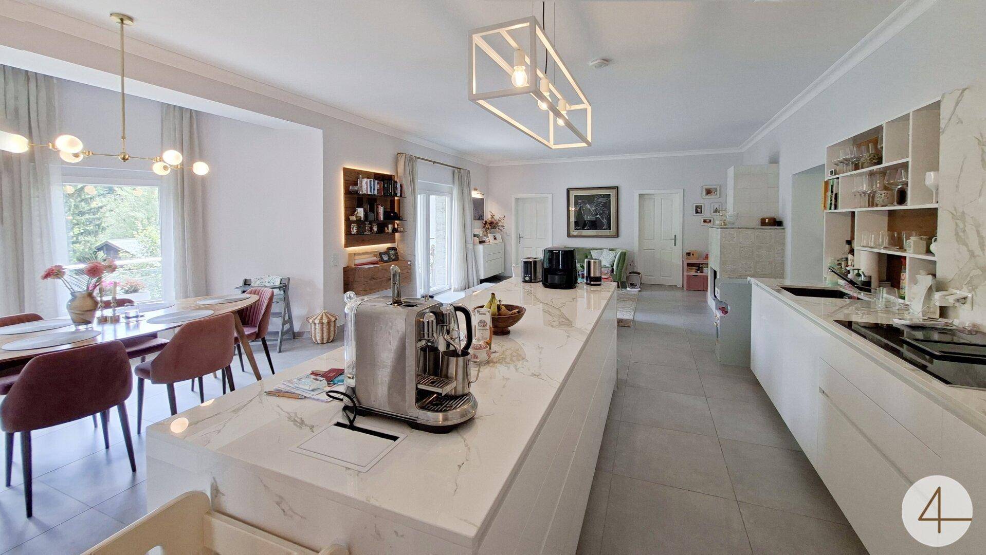 Offene Küche mit großer Insel und Essbereich, verbunden mit dem Wohnzimmer.