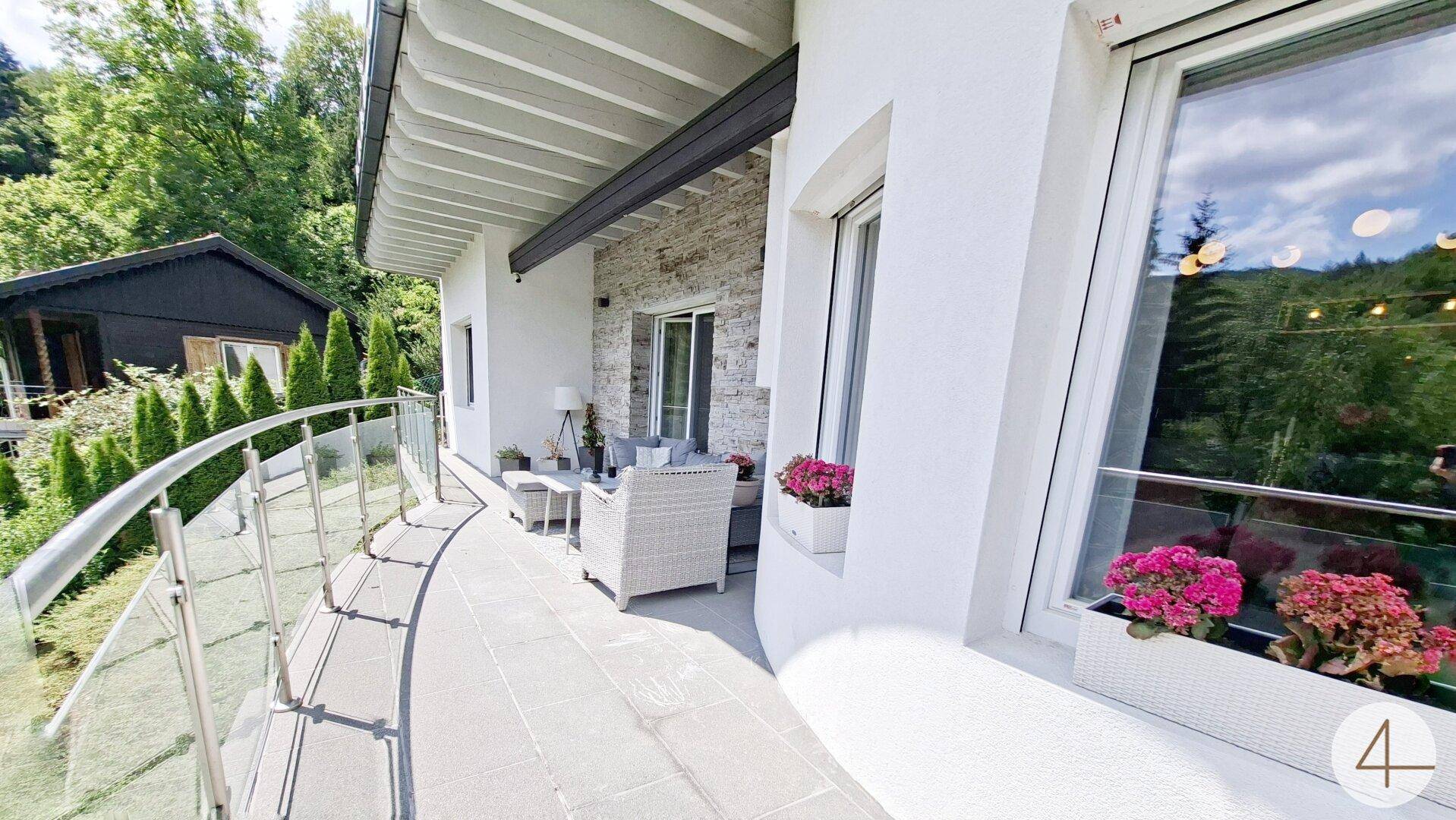 Geschwungener Balkon mit Glasgeländer und Sitzgelegenheiten, ideal zum Entspannen im Freien.