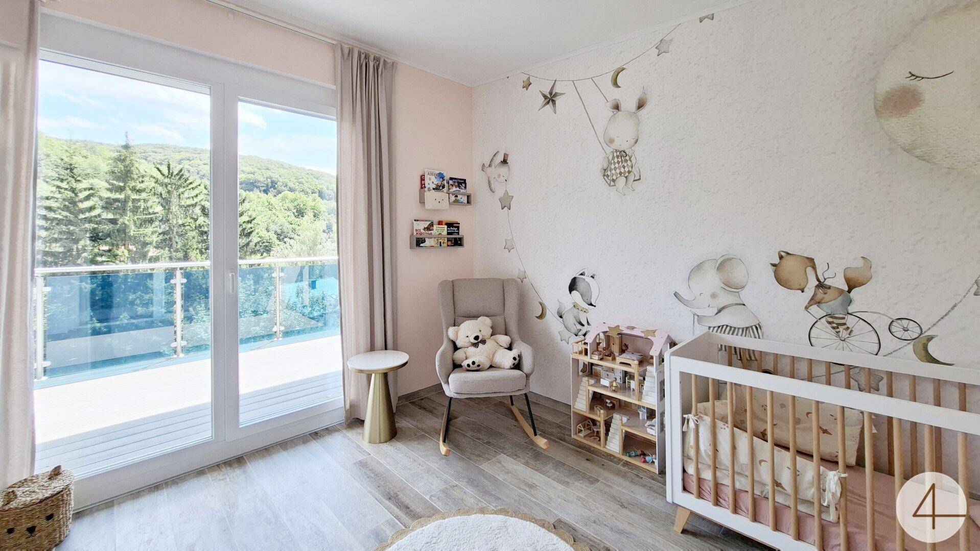 Helles Kinderzimmer mit Zugang zum Balkon, Babybett und Blick ins Grüne.