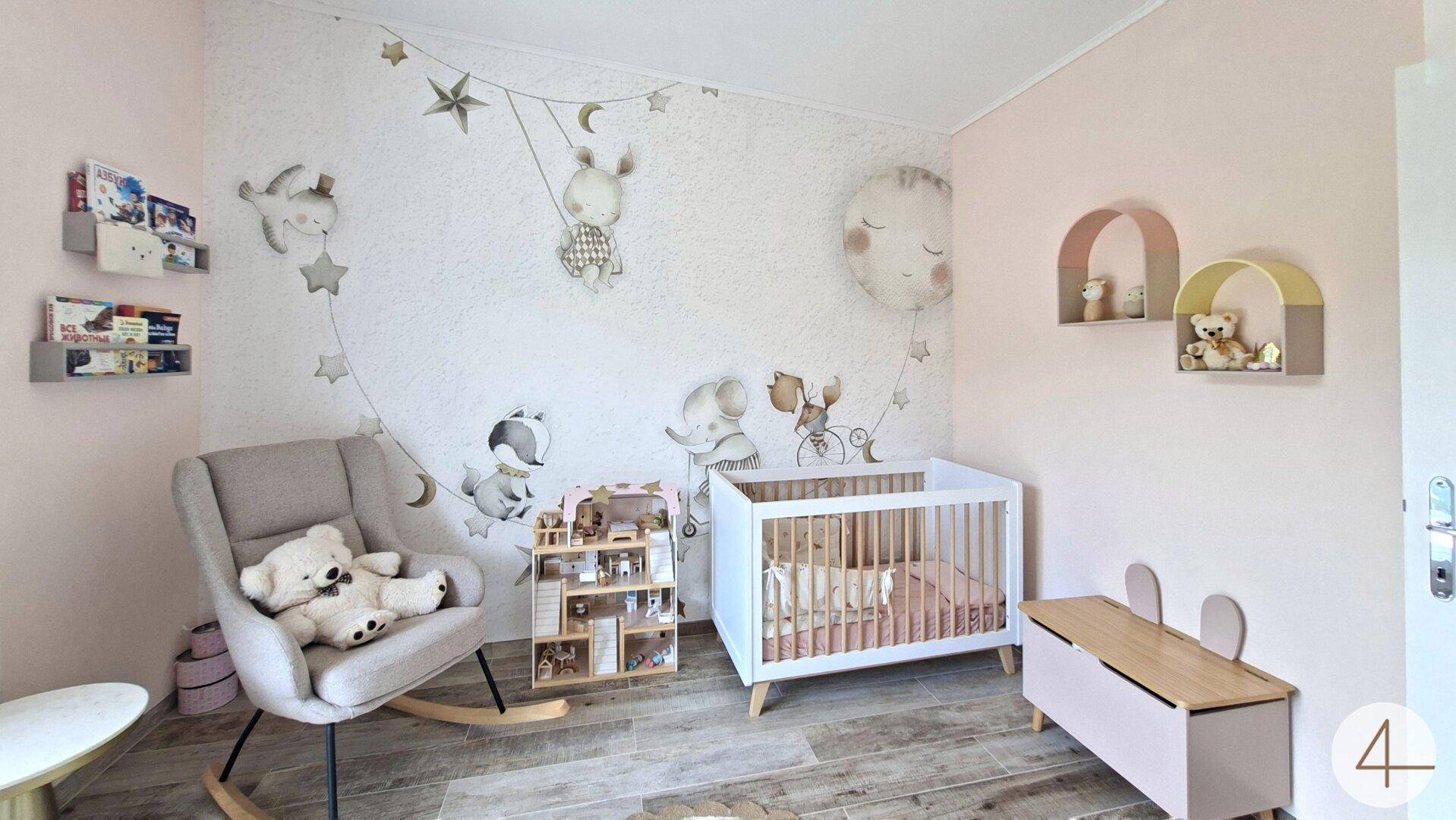 Liebevoll eingerichtetes Kinderzimmer mit Babybett, Schaukelstuhl und Wanddekoration.