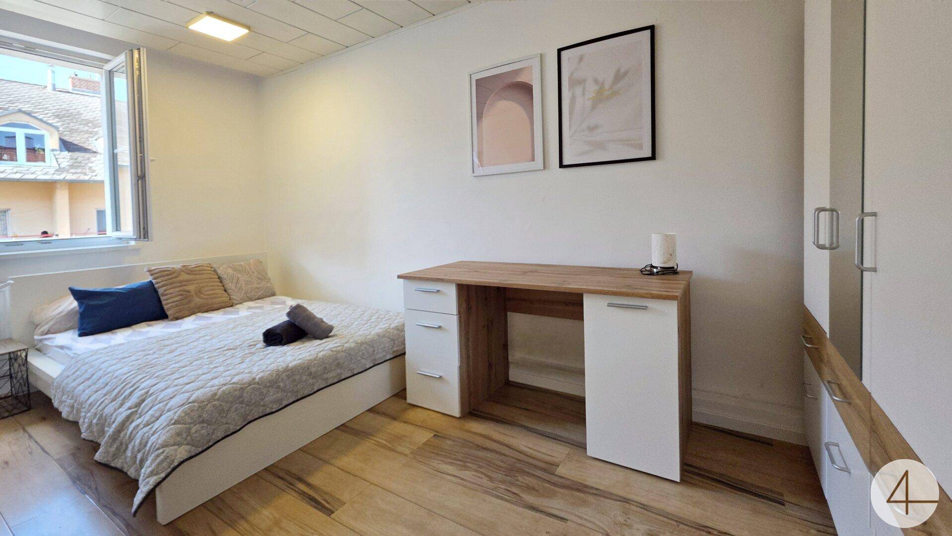 Gemütliches Schlafzimmer mit Bett, Schreibtisch und Fenster, ideal für Studenten oder Singles.