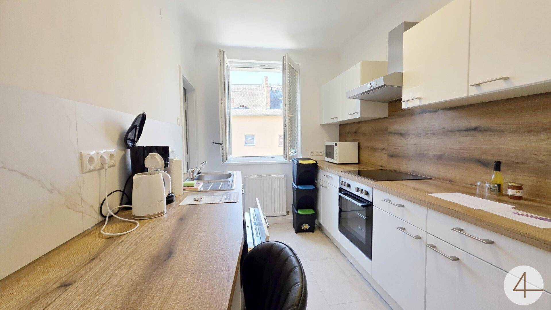 Moderne Küche mit weißen Schränken, Holz-Arbeitsplatten und integrierten Geräten.