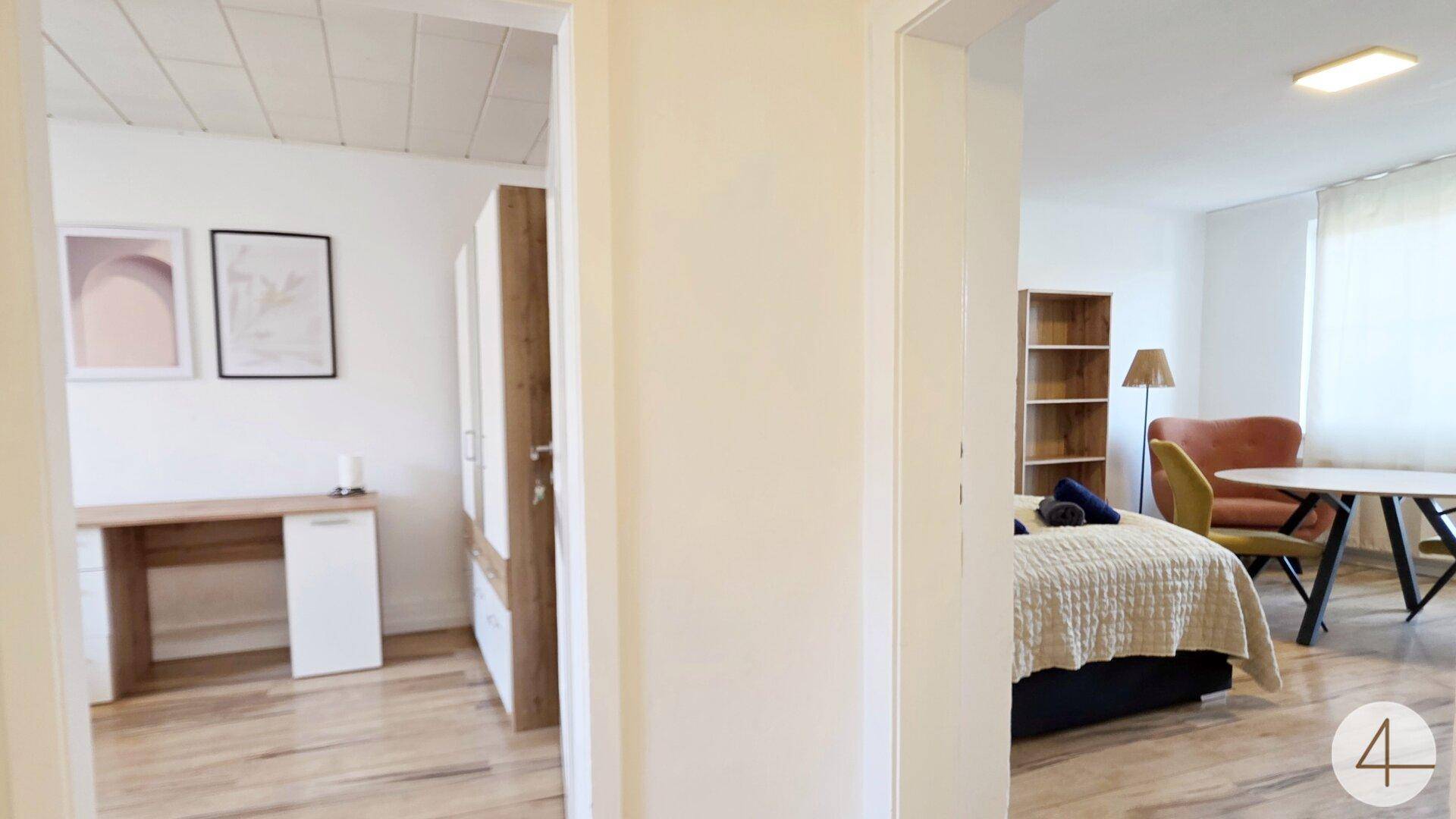 Blick vom Flur in zwei separate Zimmer mit Holzboden und moderner Einrichtung.