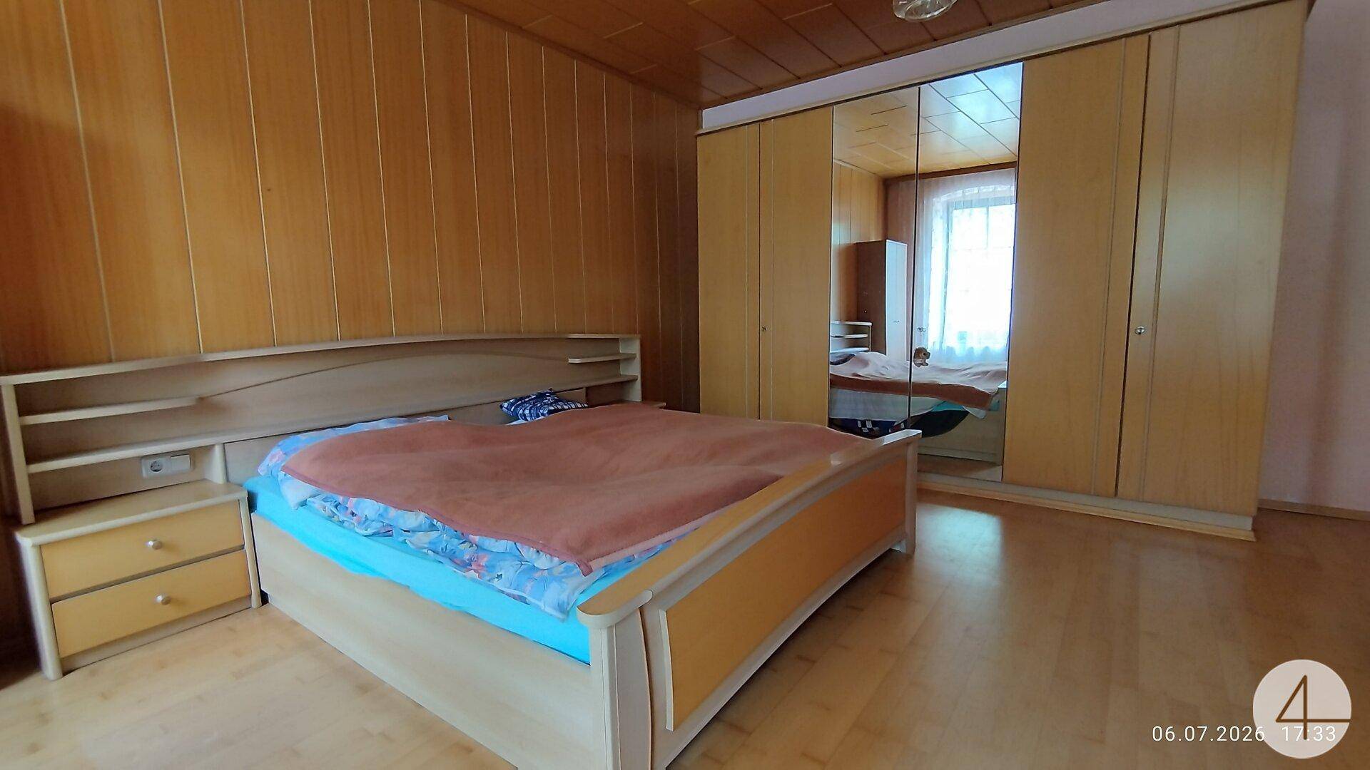 Schlafzimmer mit Holztäfelung, Doppelbett und großem Spiegelschrank.