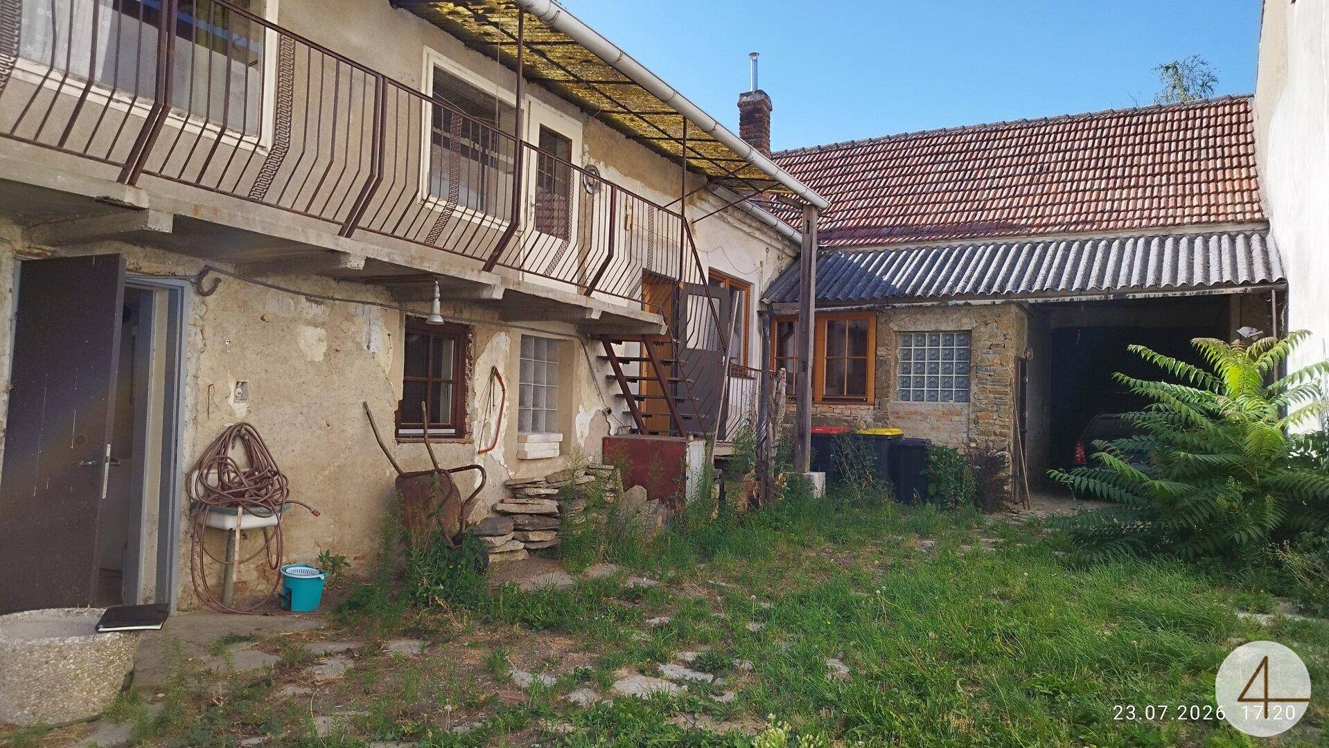 Hinterhof mit alten Gebäuden, Balkon und einer ungepflegten Rasenfläche.