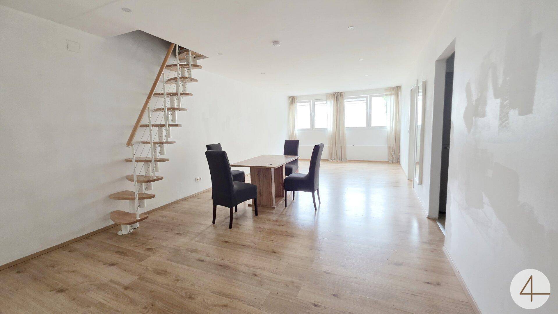 Heller offener Wohn- und Essbereich mit Holzfußboden und einer modernen Treppe.