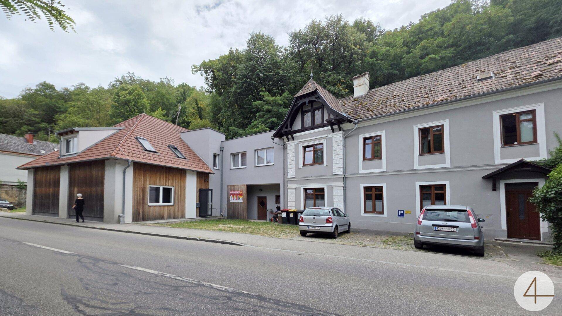 Ansicht mehrerer Gebäude entlang einer Straße, mit einem modernen Holzgebäude und älteren Häusern.