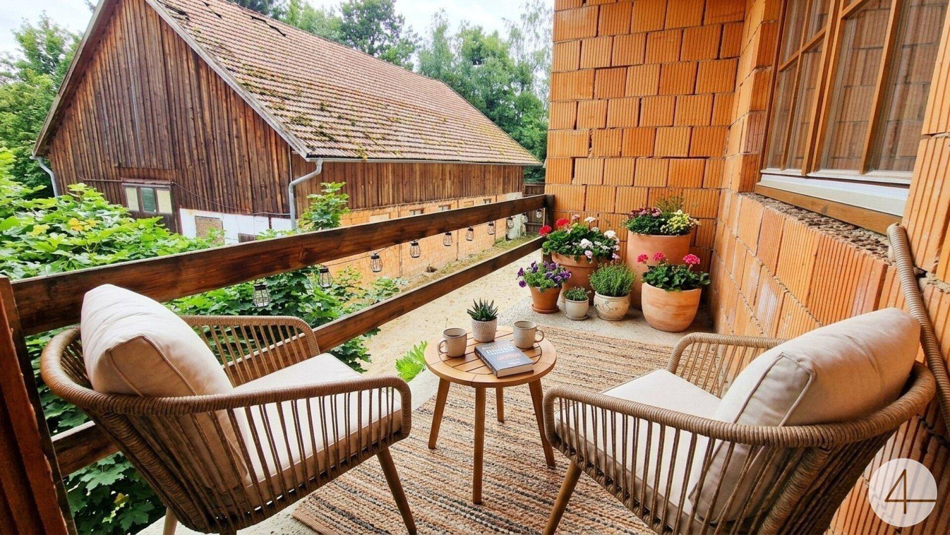 Gemütlicher Balkon mit Sitzgelegenheiten und Blick auf das ländliche Anwesen.
