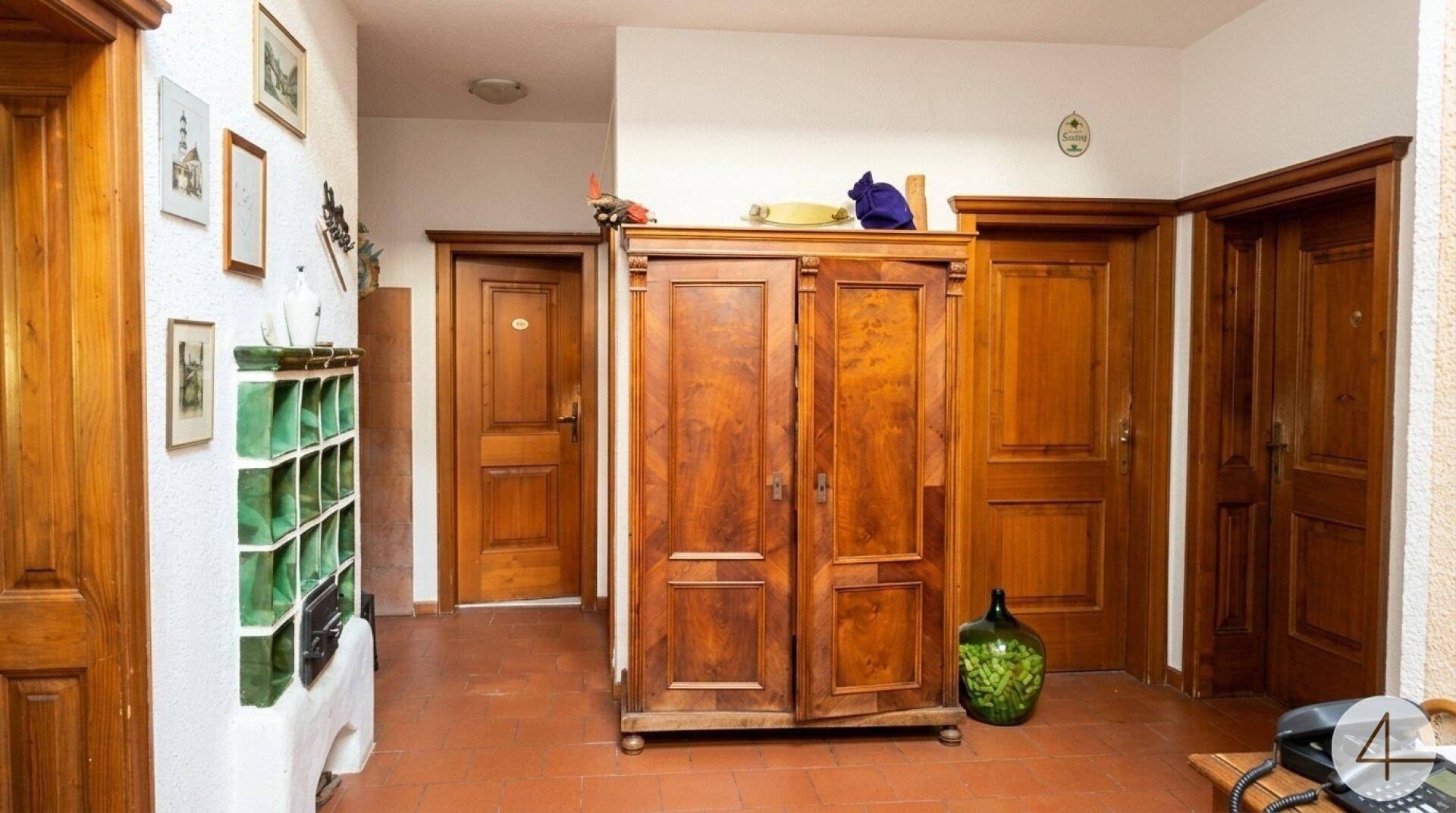 Traditioneller Eingangsbereich mit Terrakottafliesen, Holztüren und einem antiken Holzschrank.