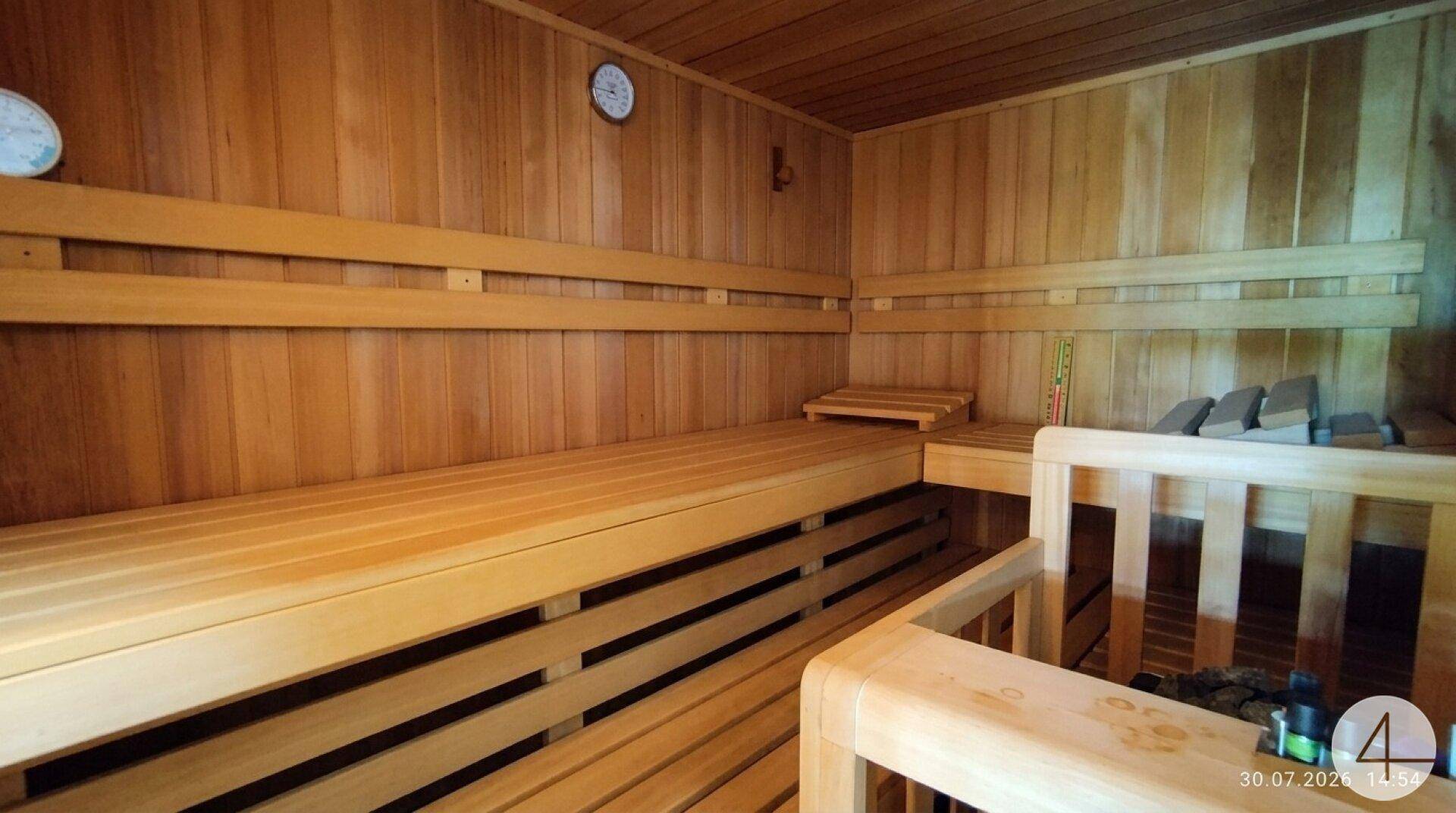 Geräumige Holzsauna mit mehreren Bänken und traditionellem Saunaofen für entspannende Momente.