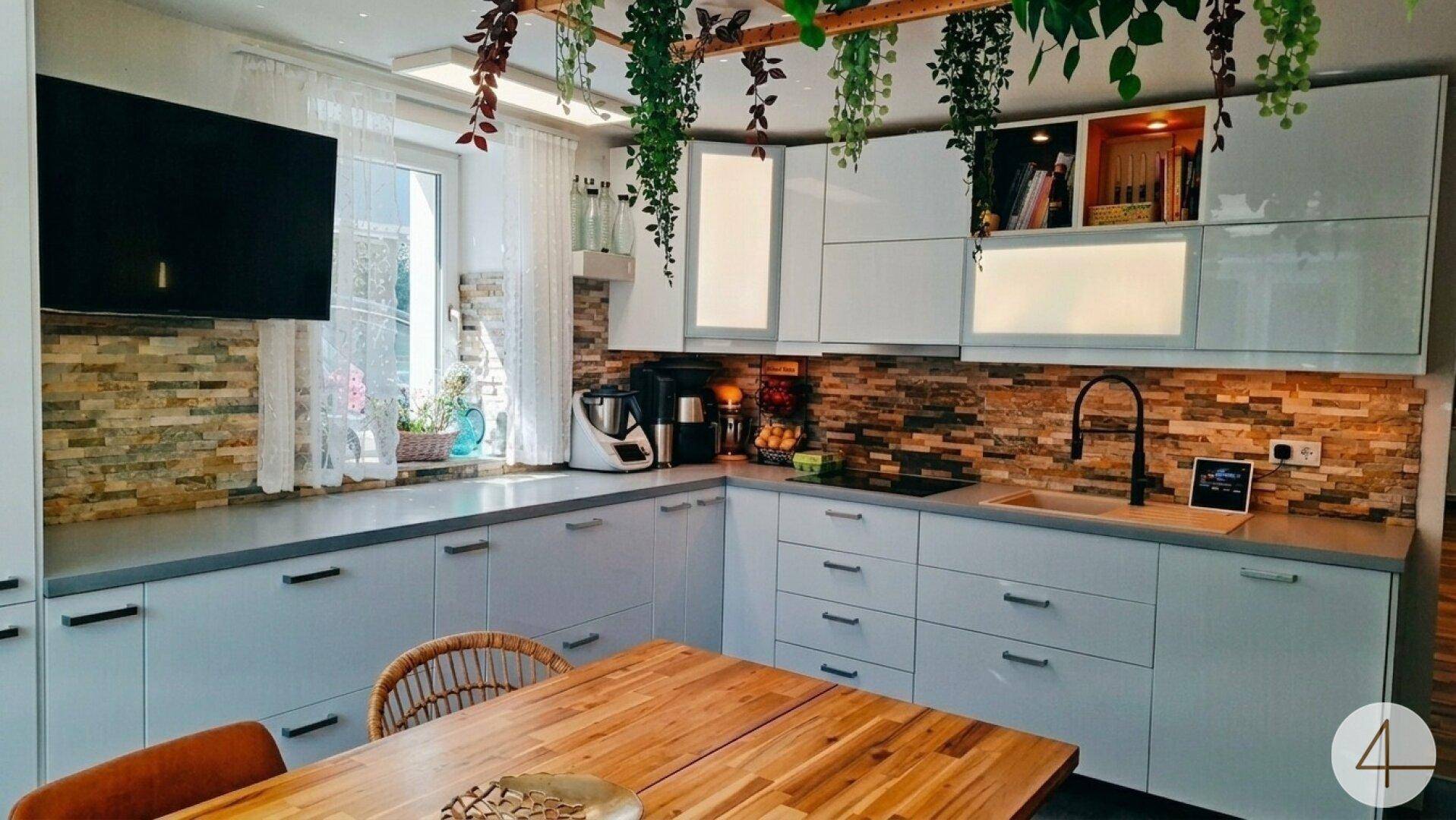 Moderne Küche mit L-förmiger Arbeitsplatte, Steinrückwand und integrierten Geräten.