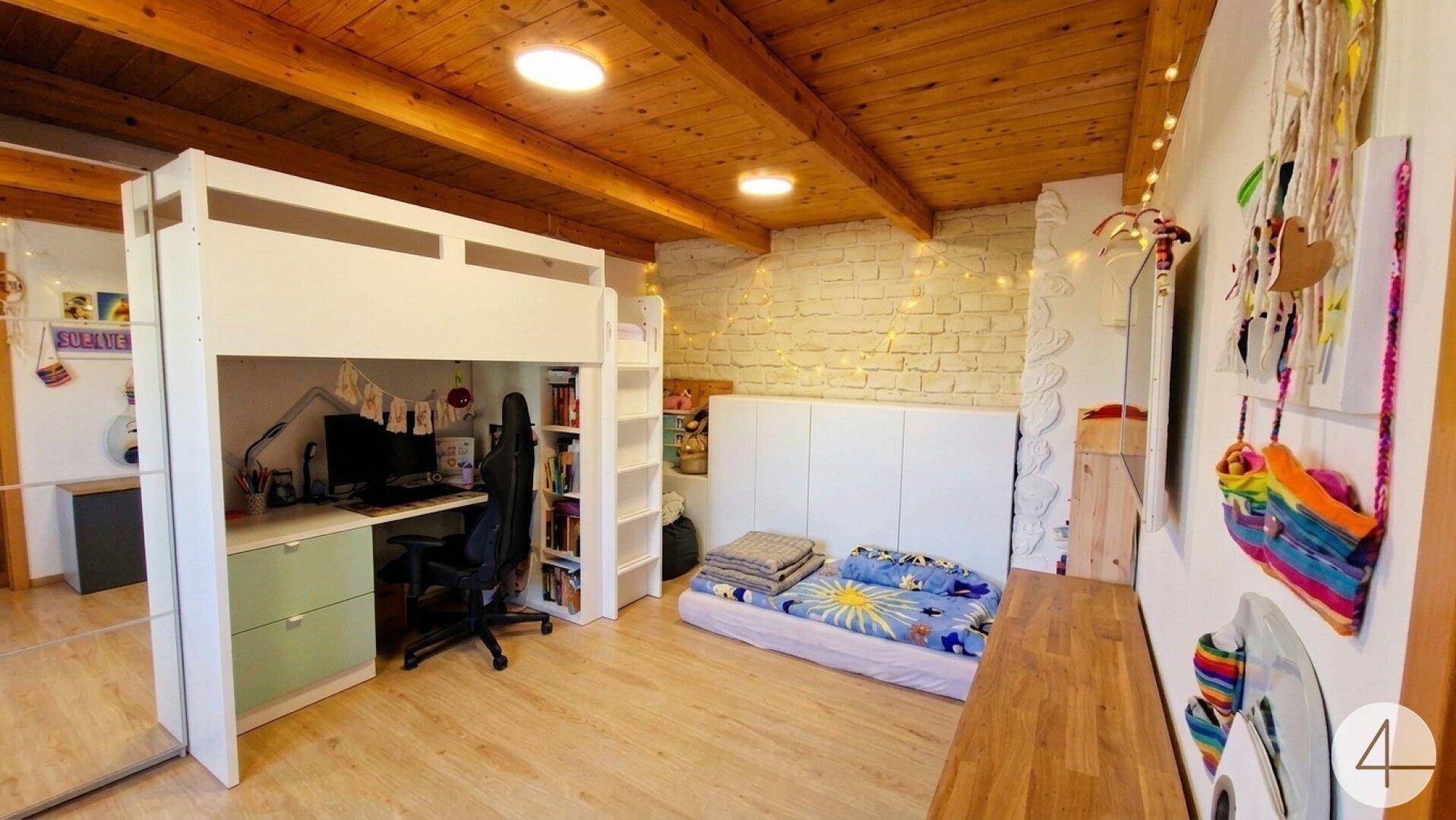 Kinderzimmer mit Hochbett, Schreibtisch und sichtbaren Holzdeckenbalken.