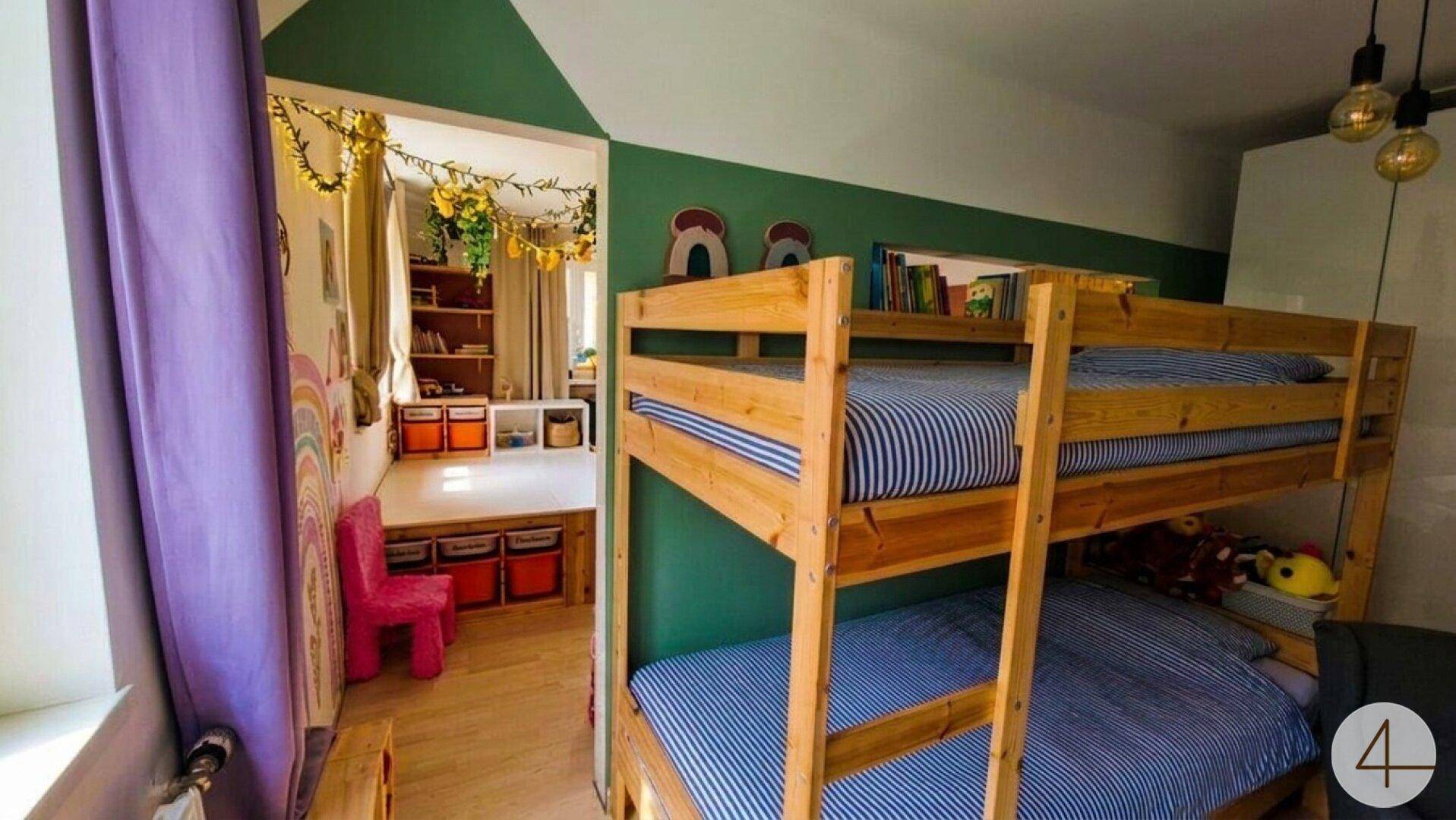 Helles Kinderzimmer mit Etagenbett und separatem Spielbereich.