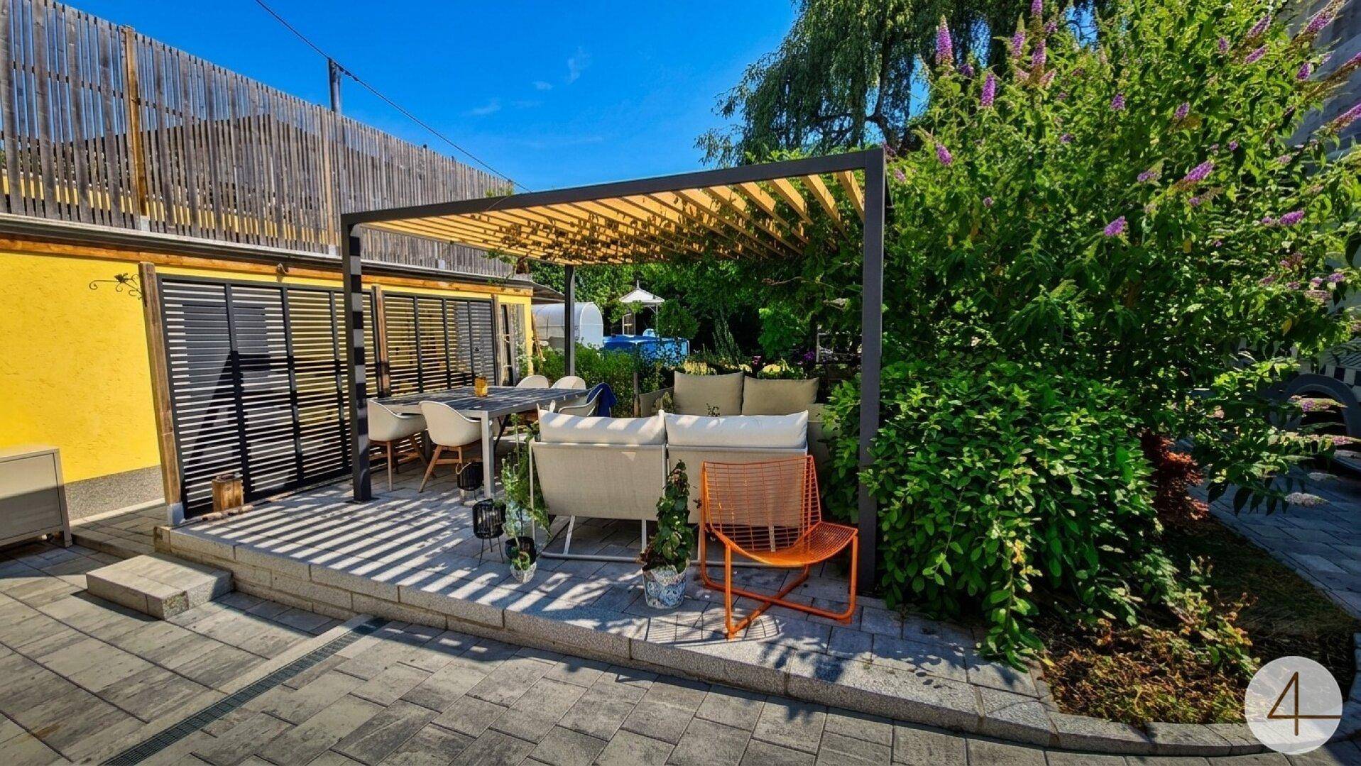 Große Terrasse mit Pergola, Essbereich und bequemen Lounge-Möbeln.