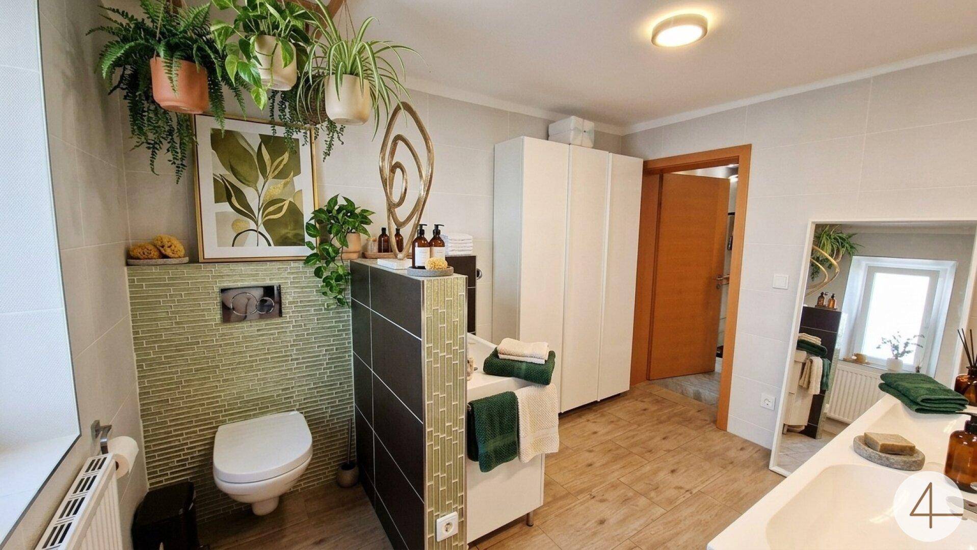 Modernes Badezimmer mit WC, grünen Mosaikfliesen und dekorativen Hängepflanzen.