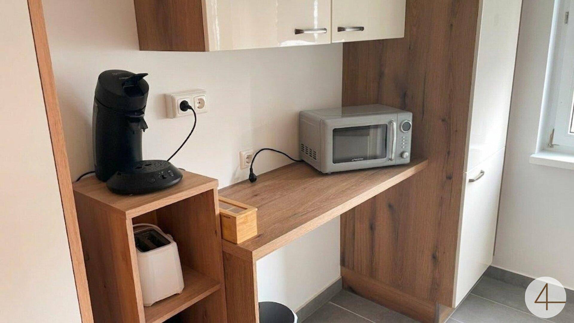 Praktische Küchenecke mit Kaffeemaschine, Mikrowelle und Toaster für den täglichen Gebrauch.