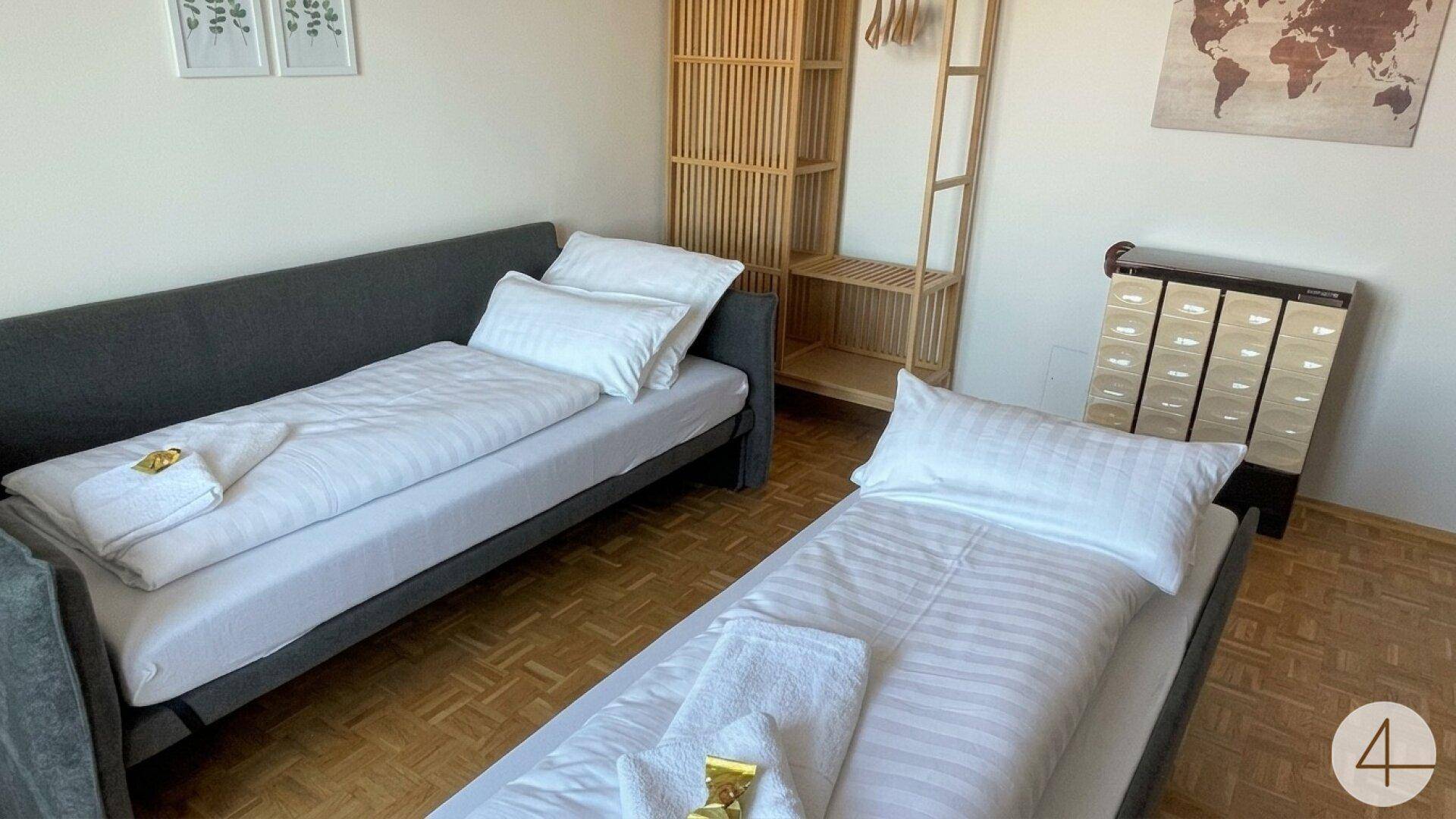 Schlafzimmer mit zwei Einzelbetten und einem offenen Holzregal, ideal für Gäste oder Kinder.