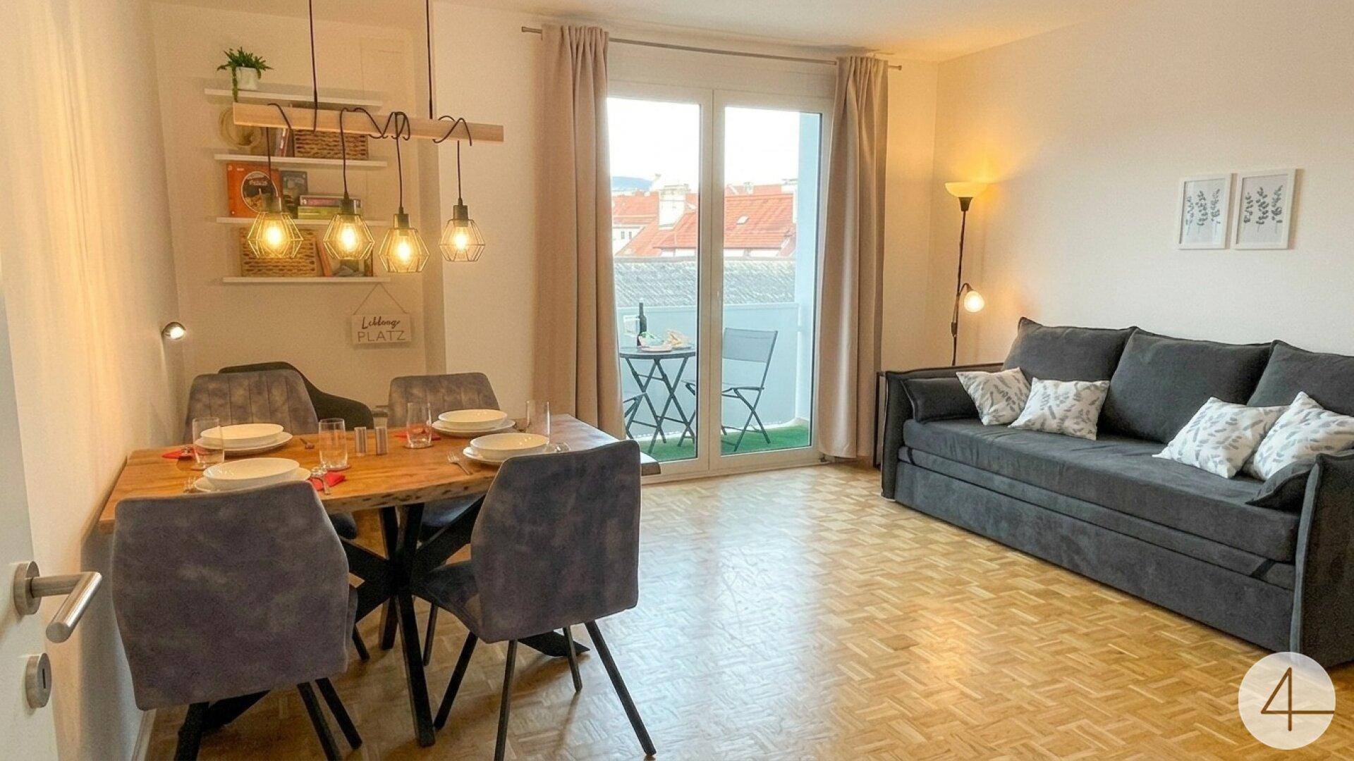 Heller Wohn-Essbereich mit Holztisch, bequemer Couch und Zugang zum Balkon mit Stadtblick.