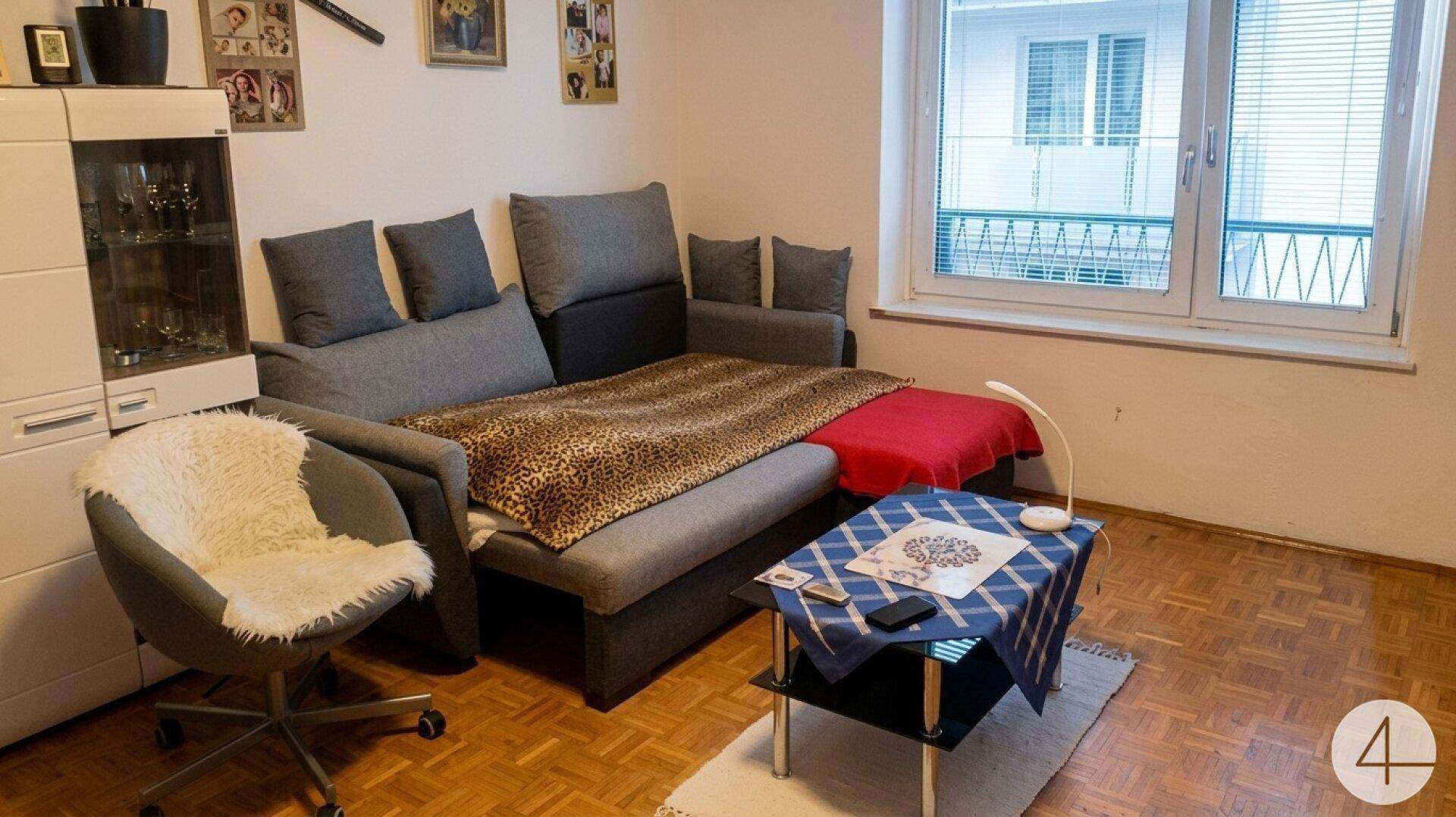 Wohnzimmer mit Schlafsofa, kleinem Couchtisch und Parkettboden, ideal für Gäste oder Entspannung.