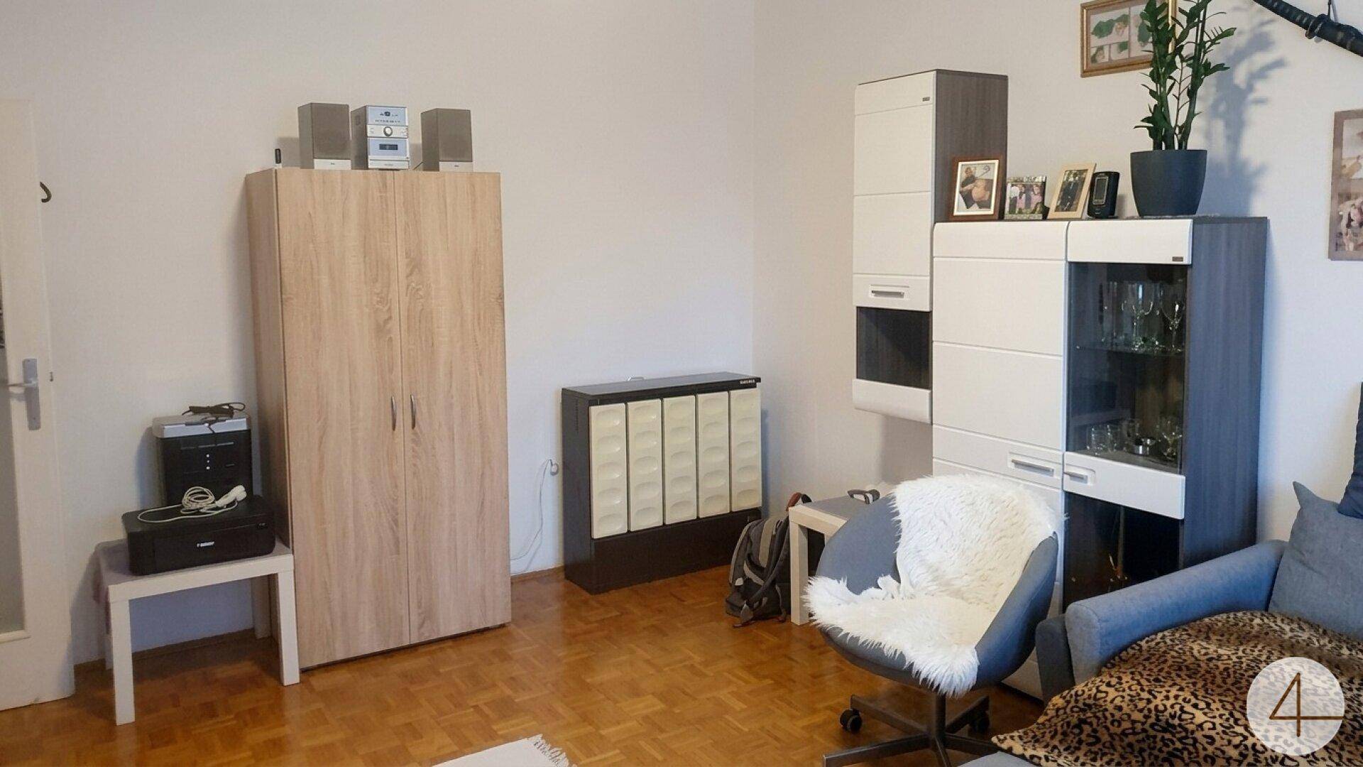 Wohnzimmer mit hellem Parkettboden, einem Kleiderschrank und modernen Wohnzimmermöbeln.