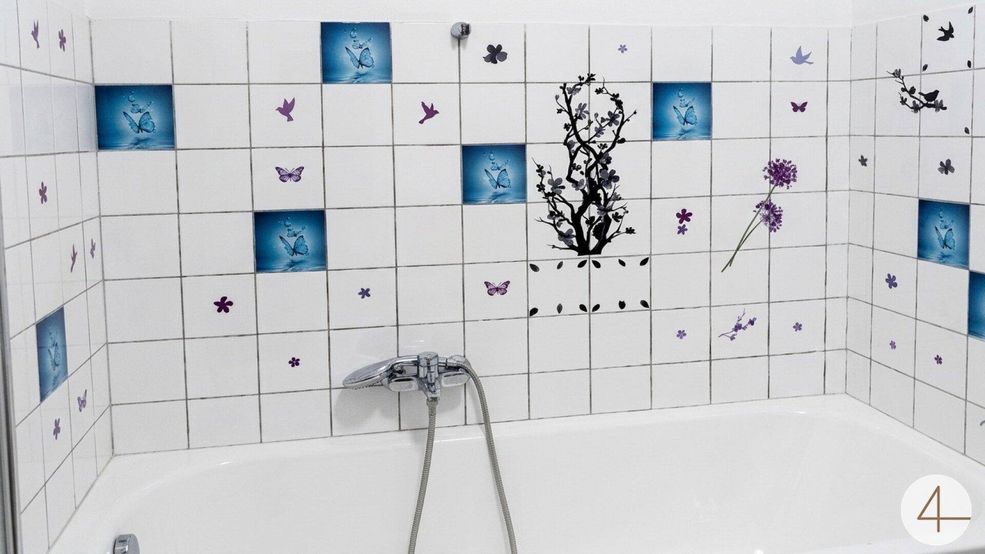 Badezimmer mit Badewanne und verspielten blauen und lila Fliesenstickern an den Wänden.