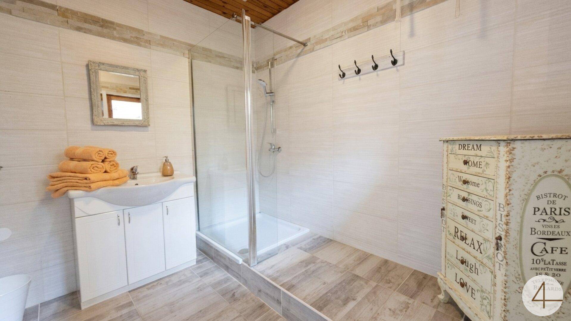 Modernes Badezimmer mit begehbarer Dusche, Einzelwaschbecken und hellen Fliesen.