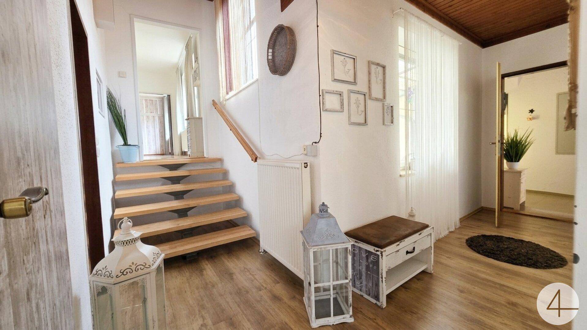 Heller Flur mit offener Holztreppe, Holzboden und rustikaler Holzdecke.