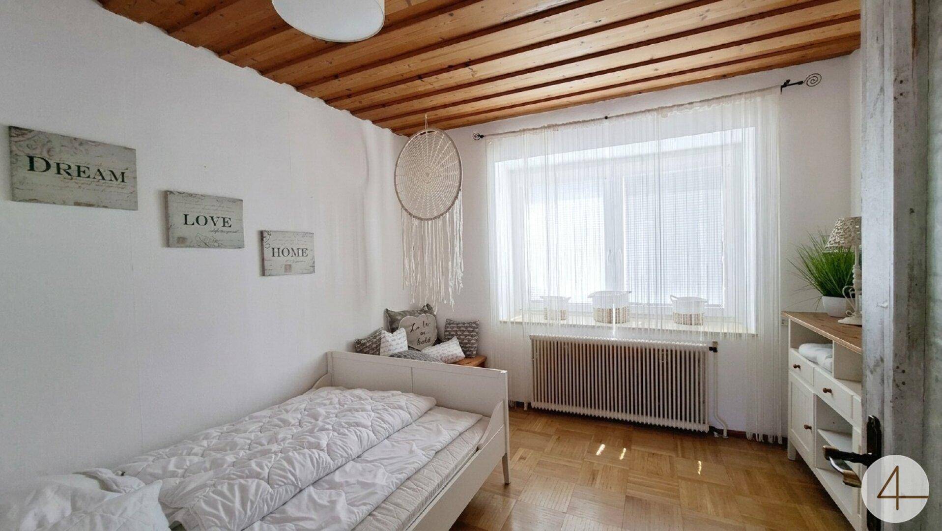 Gemütliches Schlafzimmer mit Einzelbett, Holzdecke und Parkettboden.