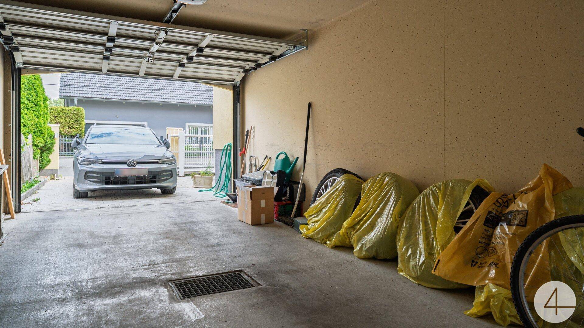 Offene Garage mit einem geparkten Auto und Blick auf die Einfahrt und die Straße.