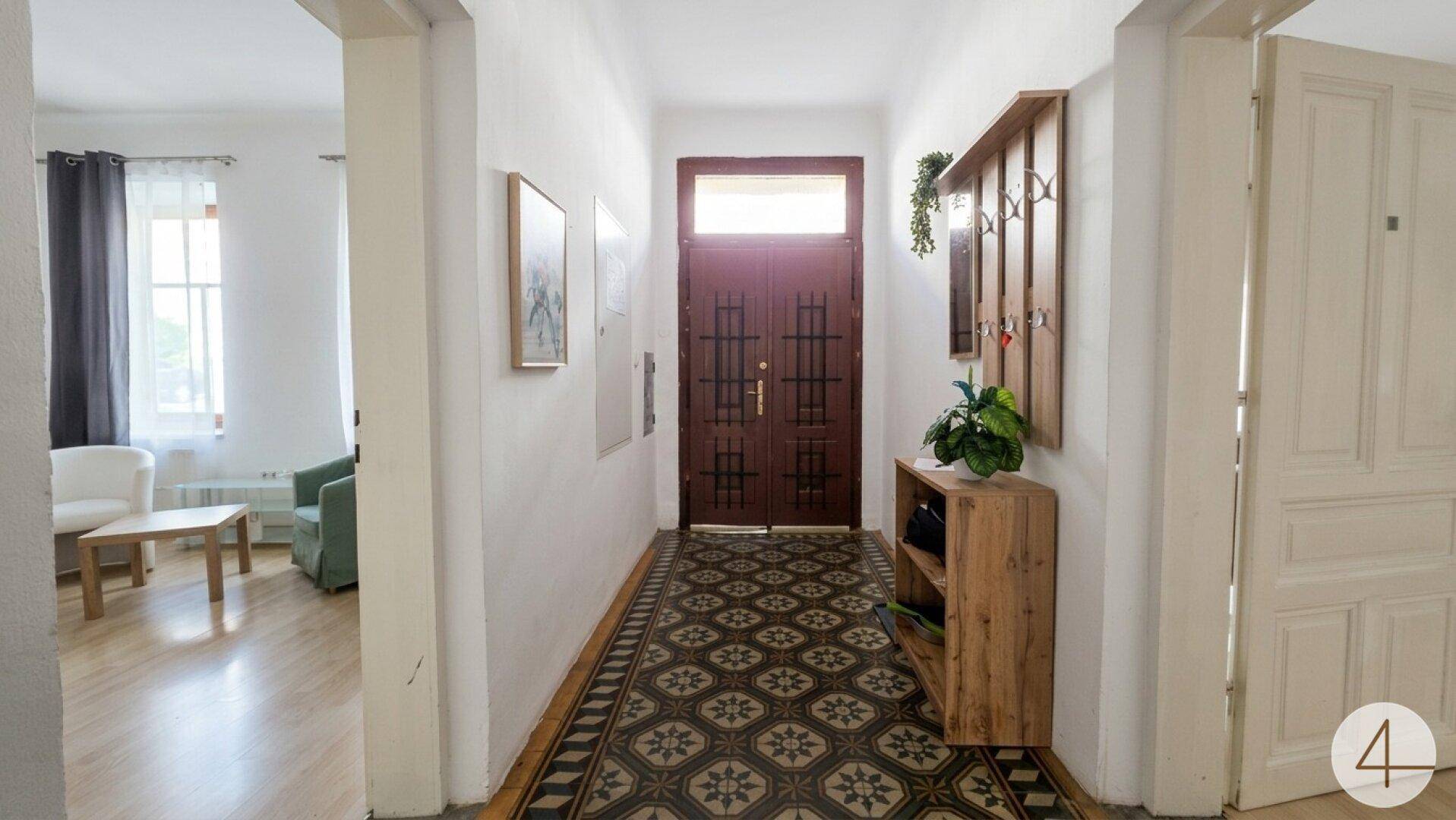 Eingangsbereich mit gemusterten Fliesen, Garderobe und Zugang zum Wohnbereich.