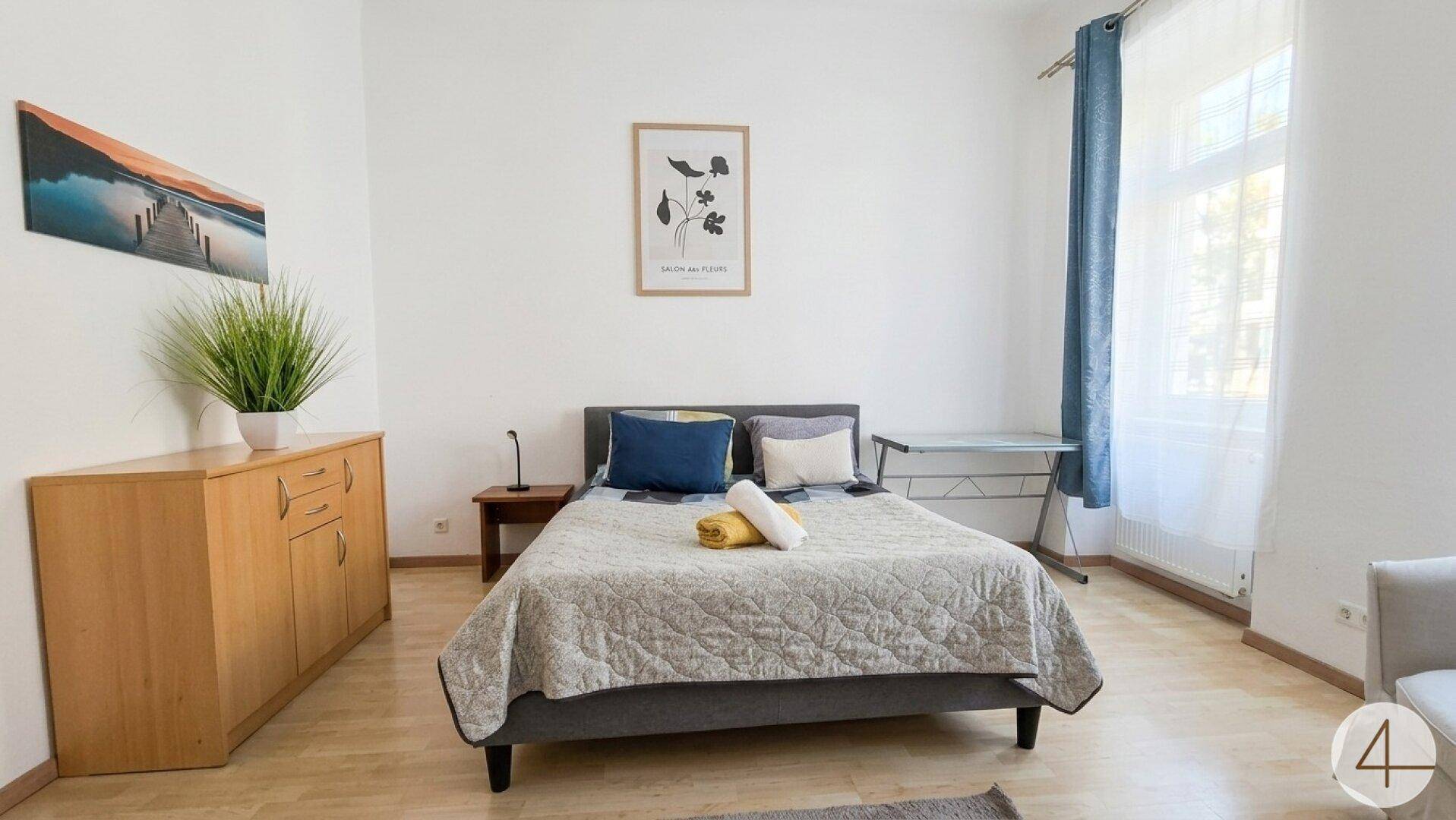Gemütliches Schlafzimmer mit Doppelbett, Holzboden und Schreibtischbereich.