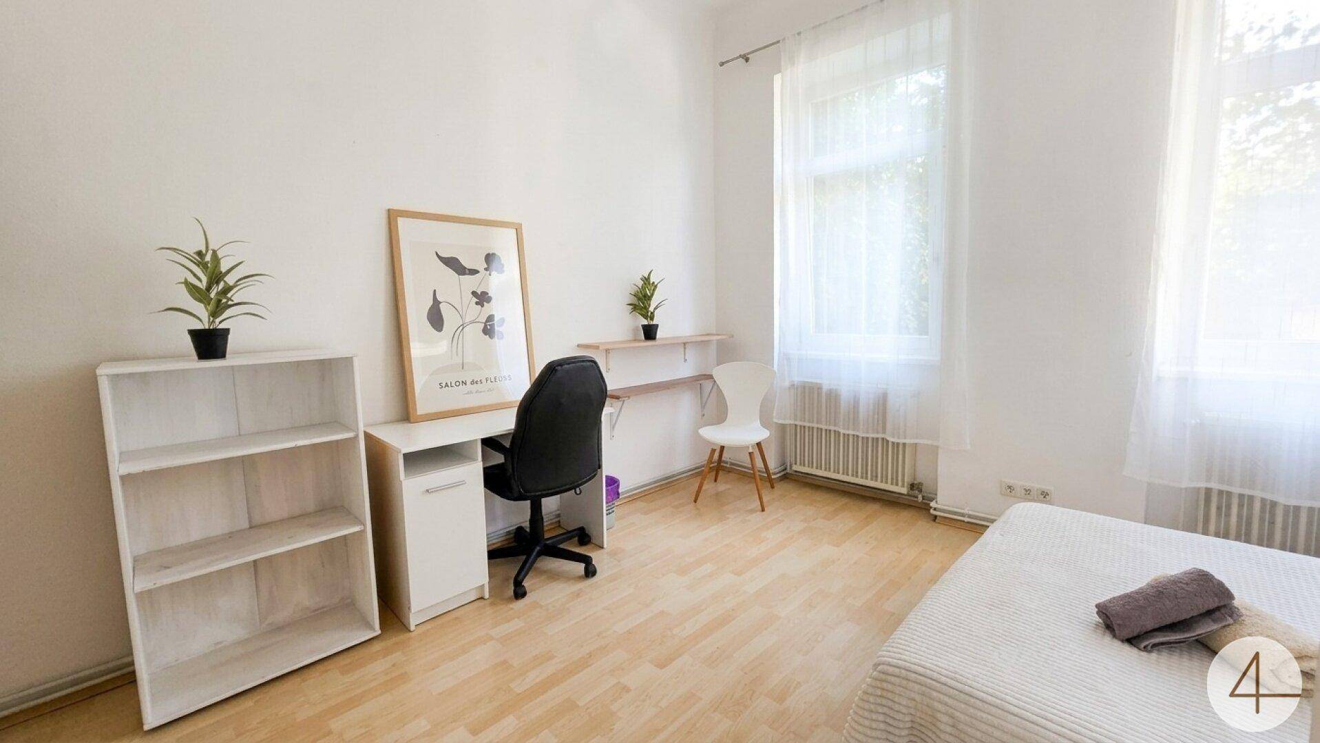 Schlafzimmer mit Schreibtisch, Regal und hellem Laminatboden.