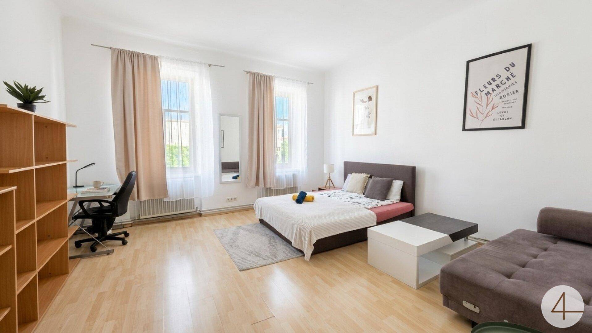 Geräumiges Schlafzimmer mit Doppelbett, Sofa und Arbeitsbereich.