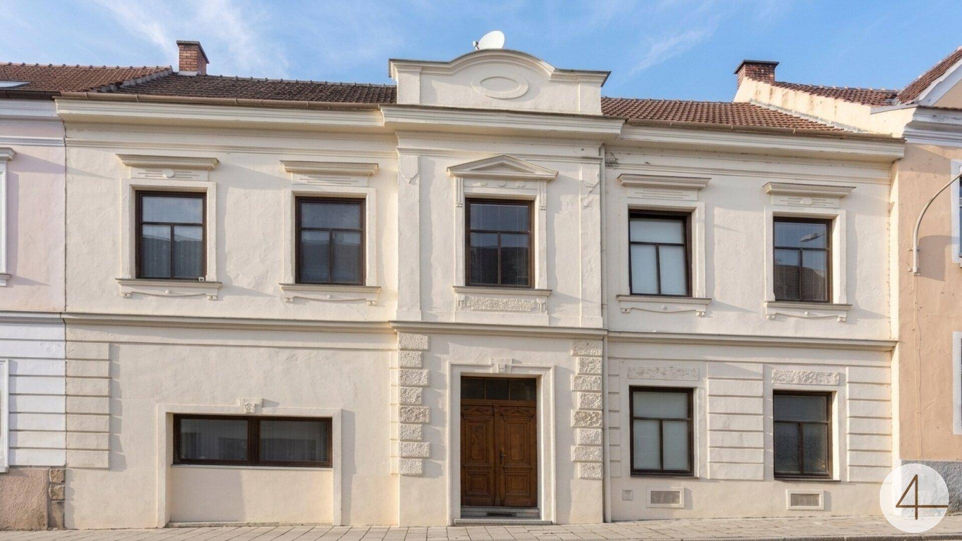 Klassische Fassade eines Wohnhauses mit mehreren Fenstern und Holztür.