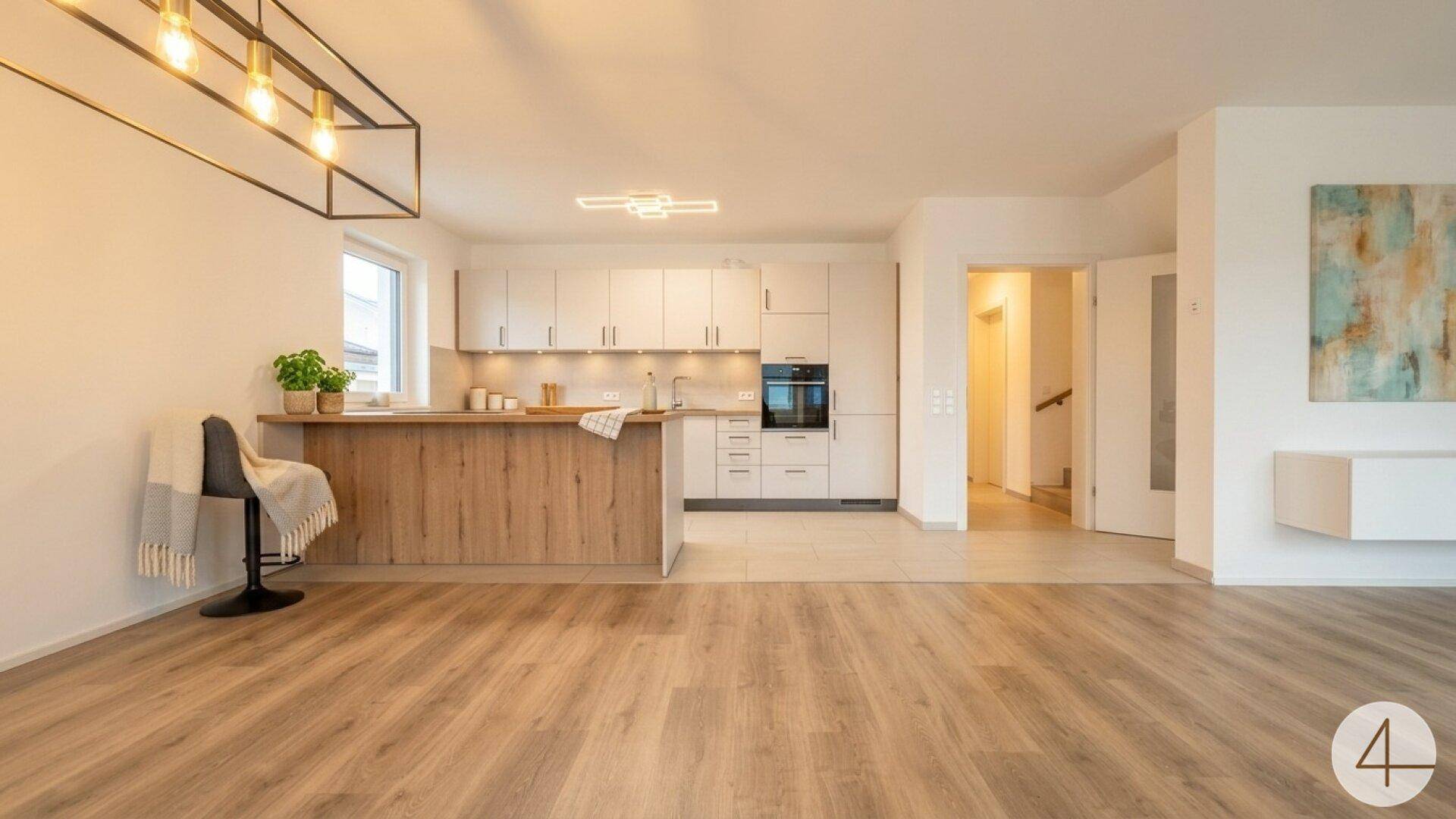 Helle, offene Küche mit weißen Schränken, Holzinsel und modernem Design, verbunden mit dem Wohnbereich.