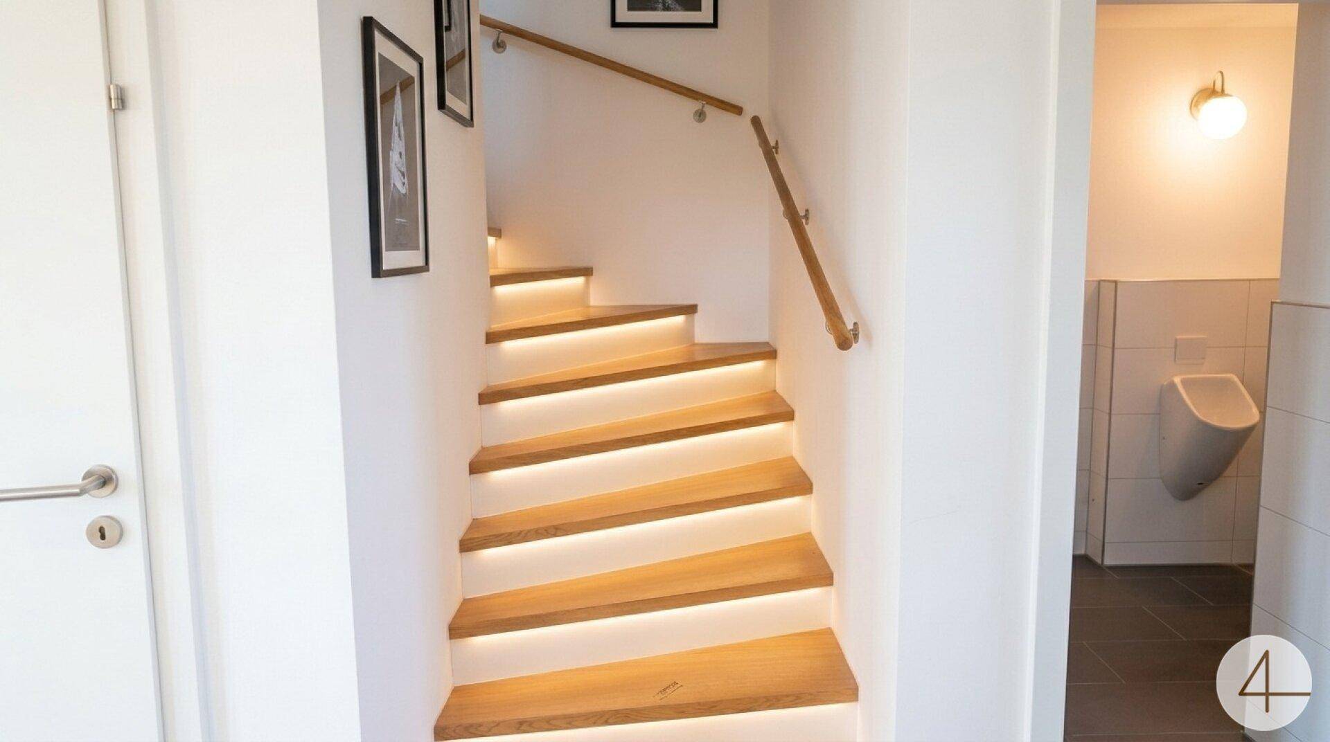 Heller Treppenaufgang mit Holzstufen und integrierter LED-Beleuchtung, angrenzend an ein Gäste-WC.