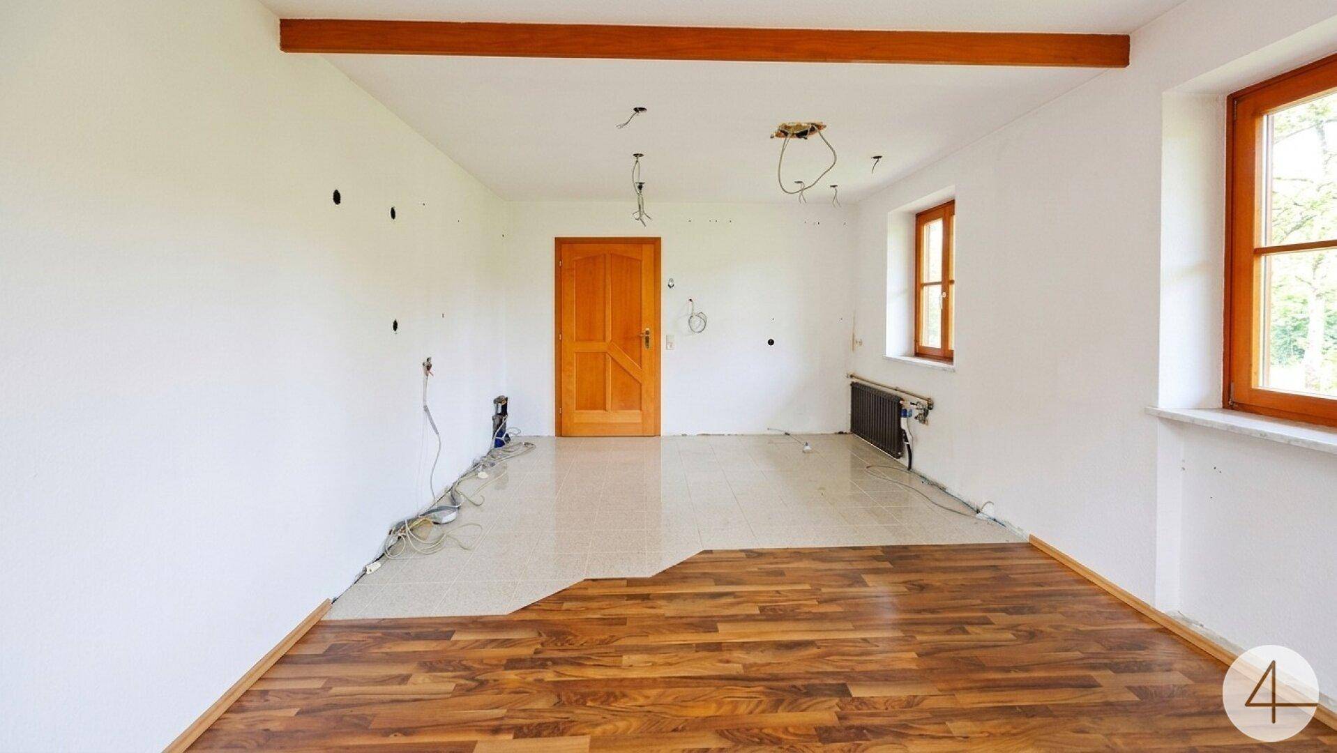 Raum in Renovierung mit teilweise verlegtem Holzboden und sichtbaren Kabeln.
