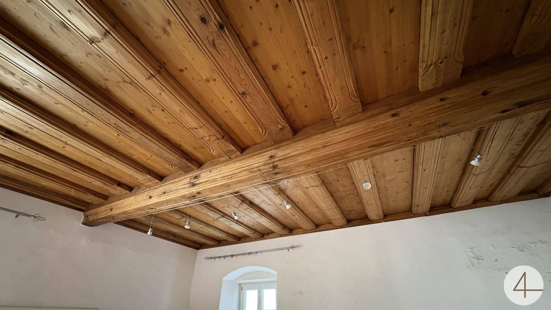 Detailaufnahme der rustikalen Holzbalkendecke, die dem Raum einen warmen und traditionellen Charakter verleiht.