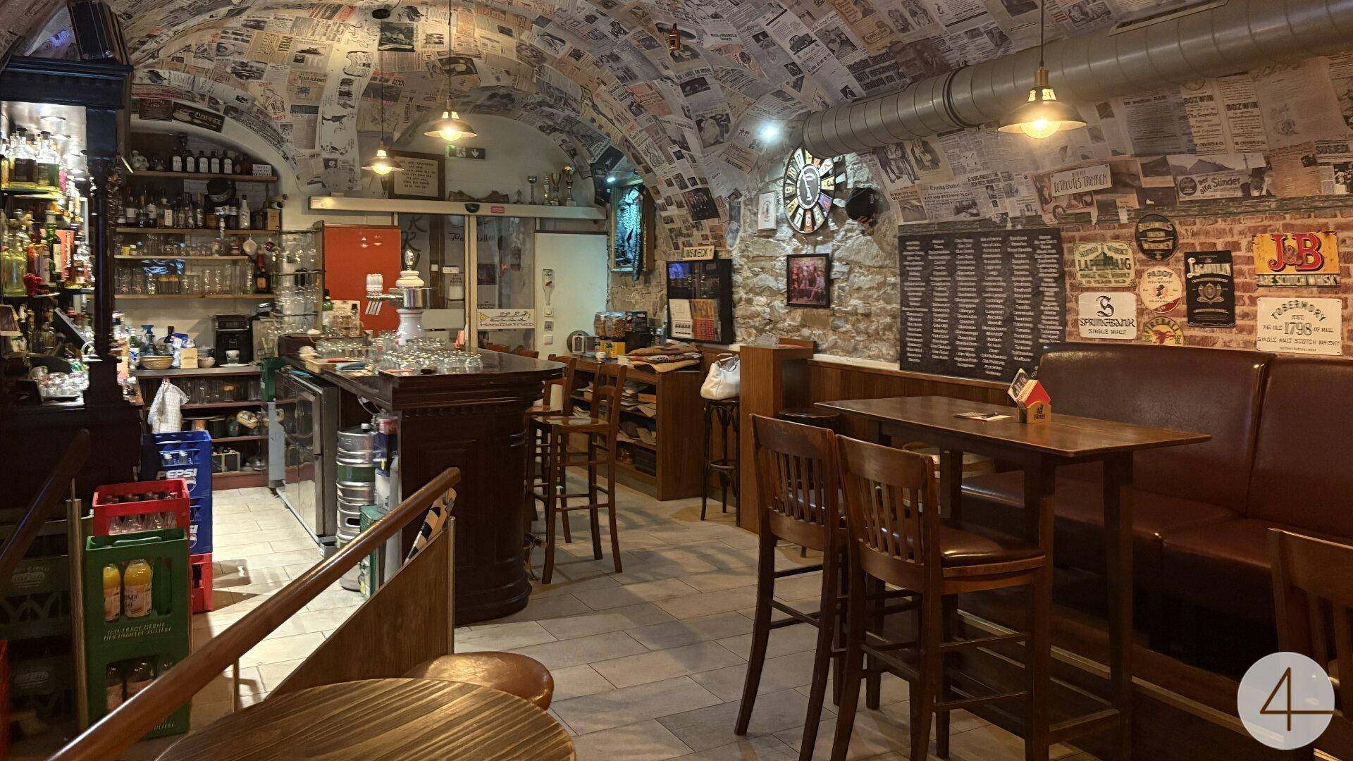 Geräumiger Pub-Innenraum mit langer Bar, gemütlichen Sitzgelegenheiten und einer einzigartigen Deckenverkleidung.