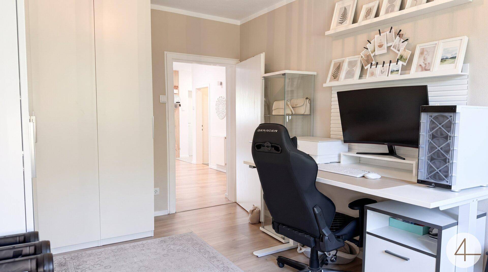 Helles Arbeitszimmer mit modernem Schreibtisch, Computer und weißem Einbauschrank.