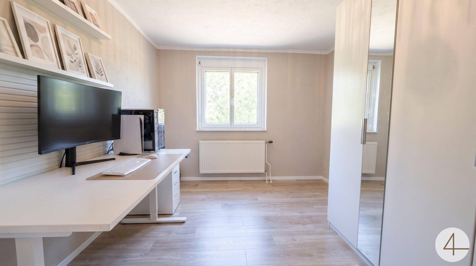 Modernes Arbeitszimmer mit Schreibtisch, Computer und großem Spiegelschrank.