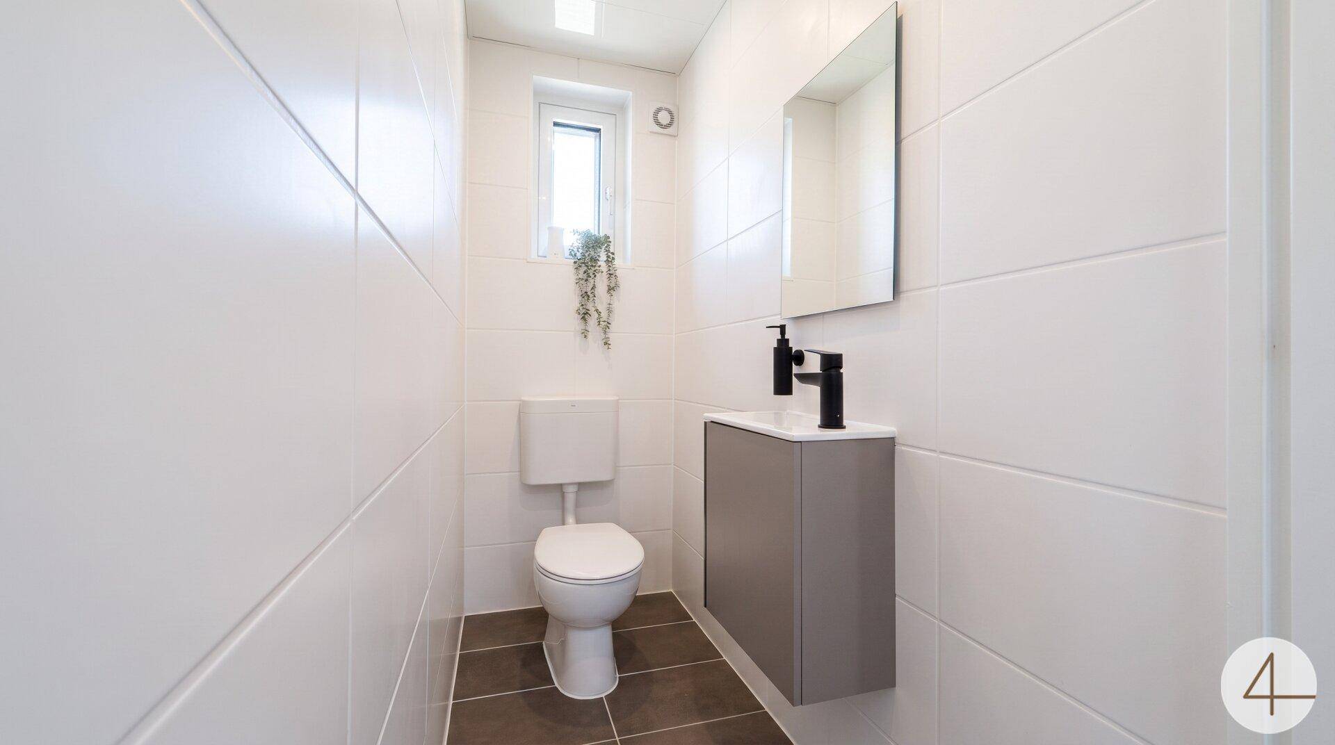 Modernes Gäste-WC mit wandhängendem WC, kleinem Waschbecken und Fenster.