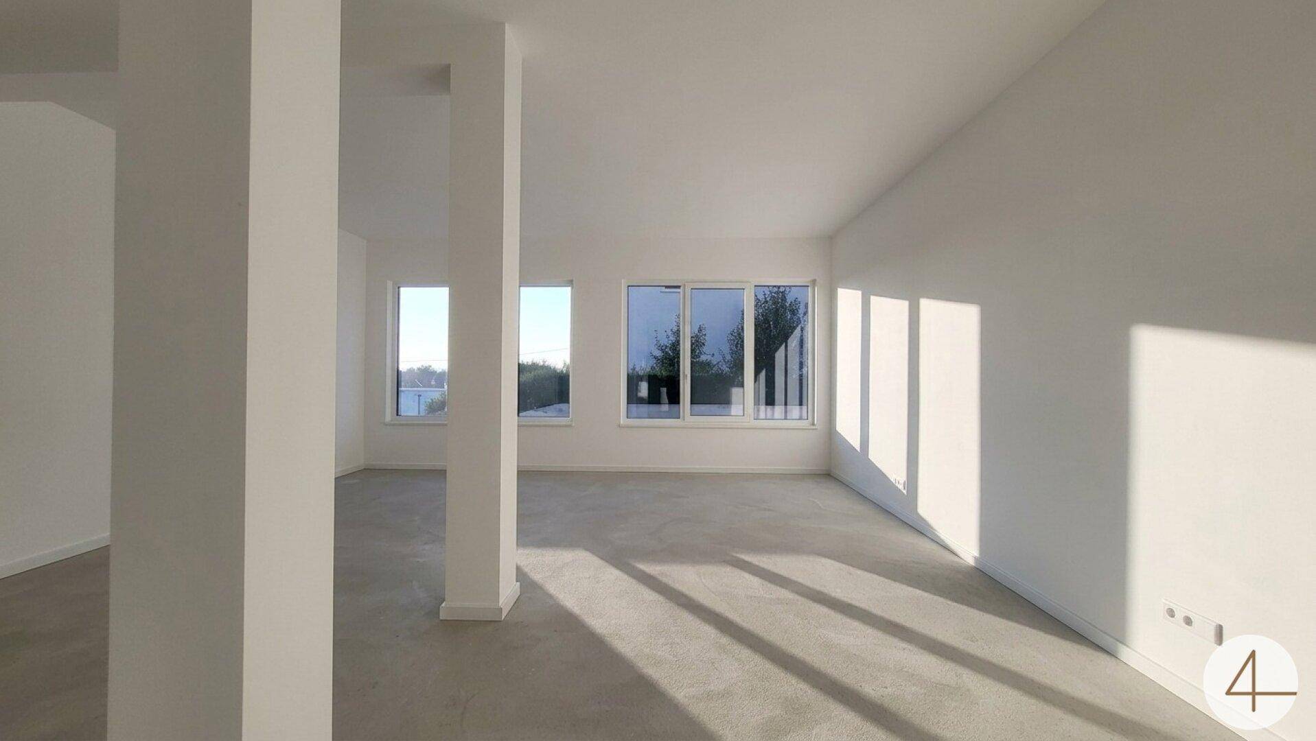 Großer, heller Raum mit Betonboden und vielen Fenstern, bereit für individuelle Gestaltung.