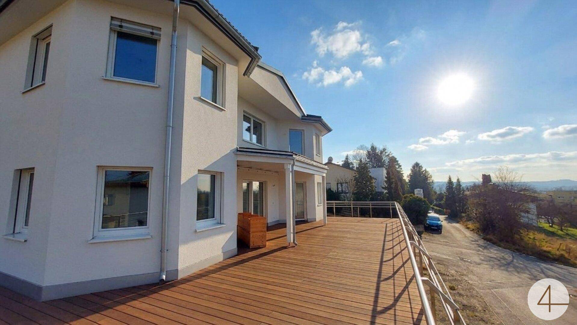 Geräumige Holzterrasse mit modernem Geländer und sonnigem Ausblick auf die Umgebung.